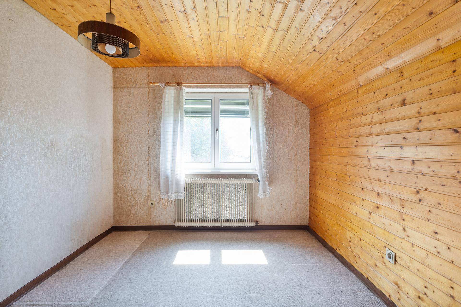 Helles Schlafzimmer im Dachgeschoss mit Holzverkleidung und Fenster.