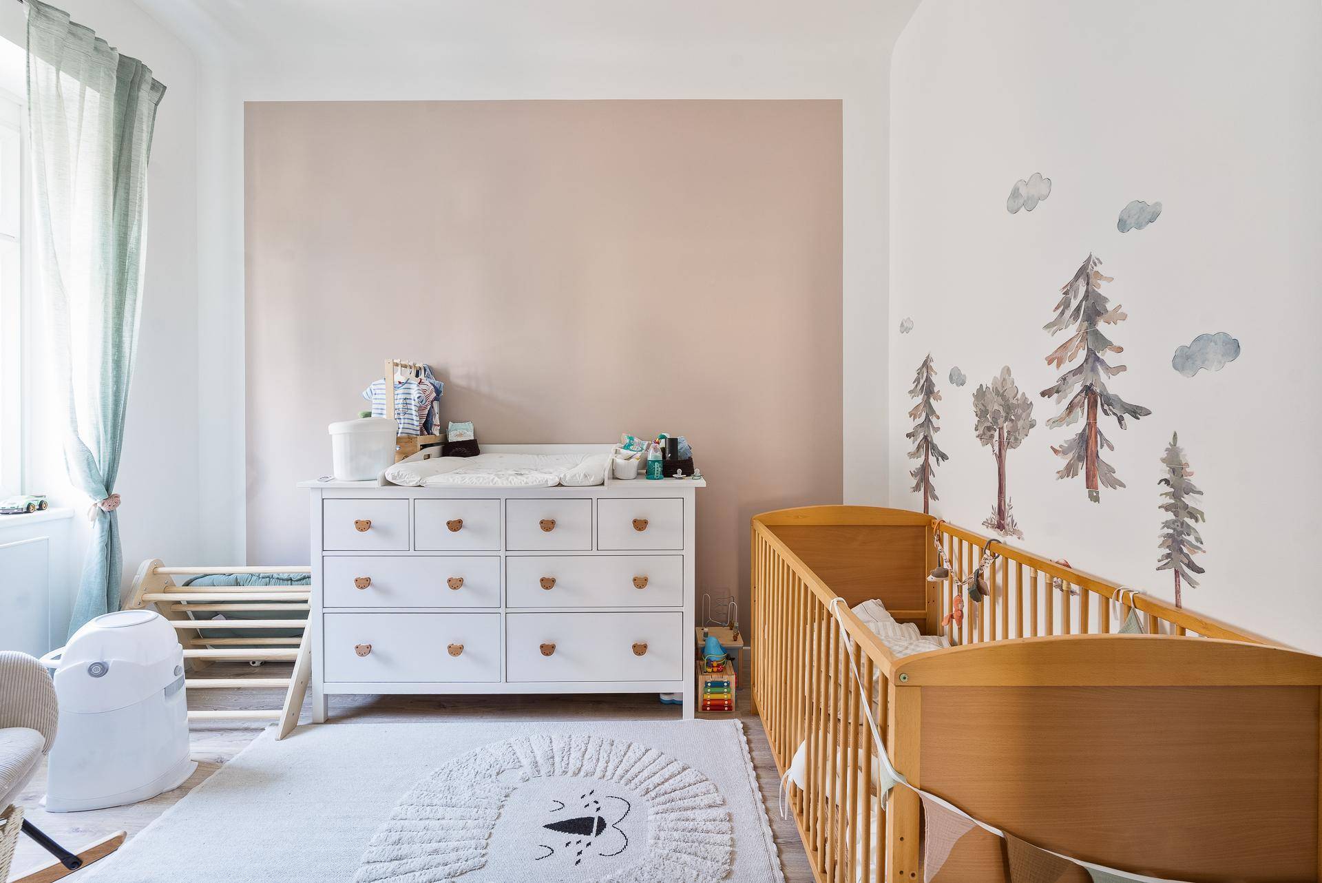 Freundliches Kinderzimmer mit Babybett, Wickelkommode und verspielter Wanddekoration.