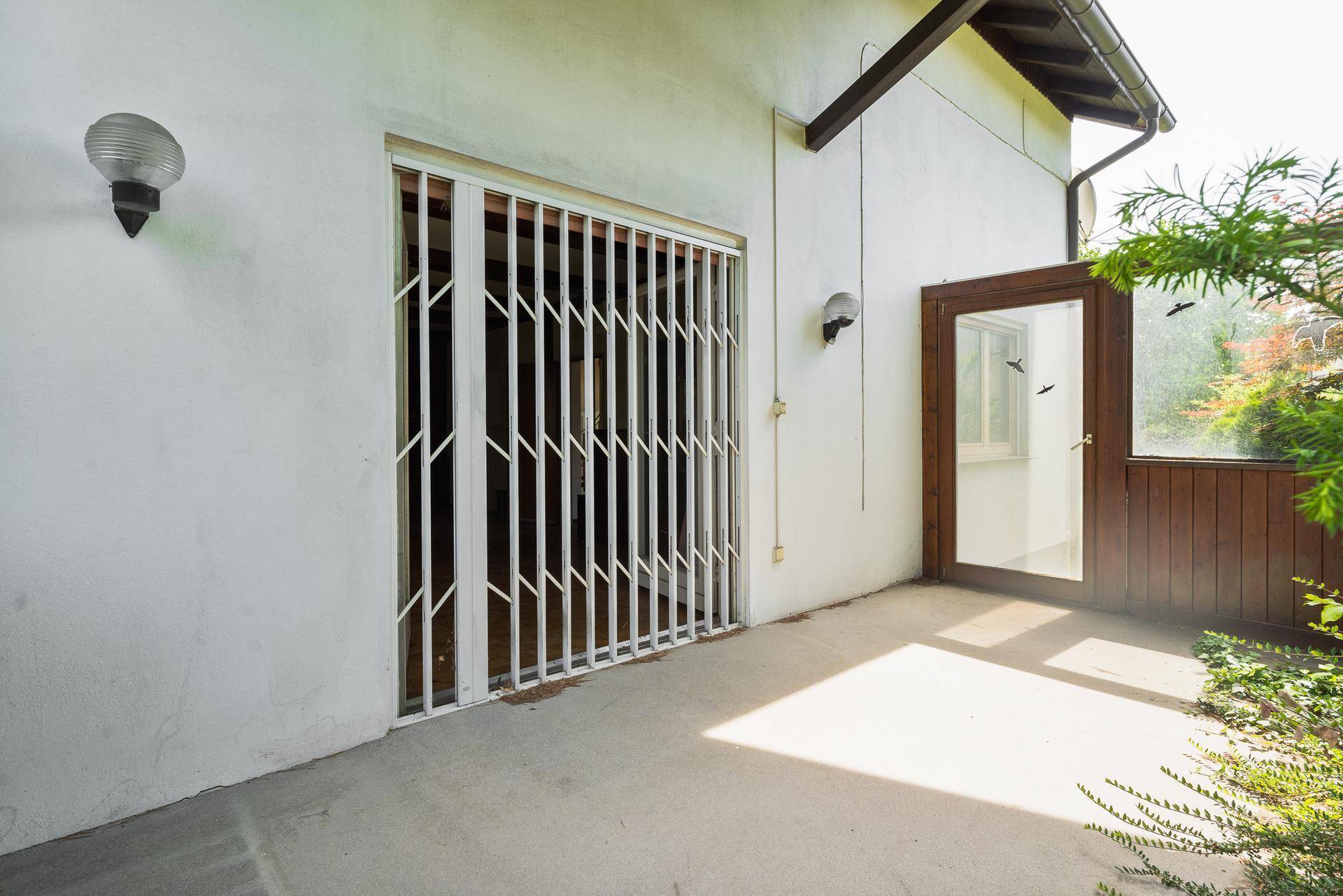 Überdachte Terrasse mit ausziehbarer Sicherheitstür und Zugang zum Gartenbereich.