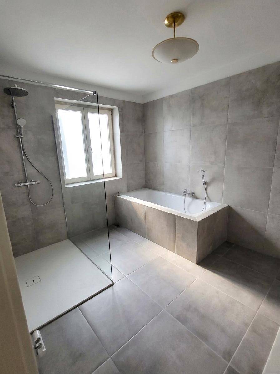 Helles Badezimmer mit ebenerdiger Dusche, Badewanne und Fenster für natürliches Licht.
