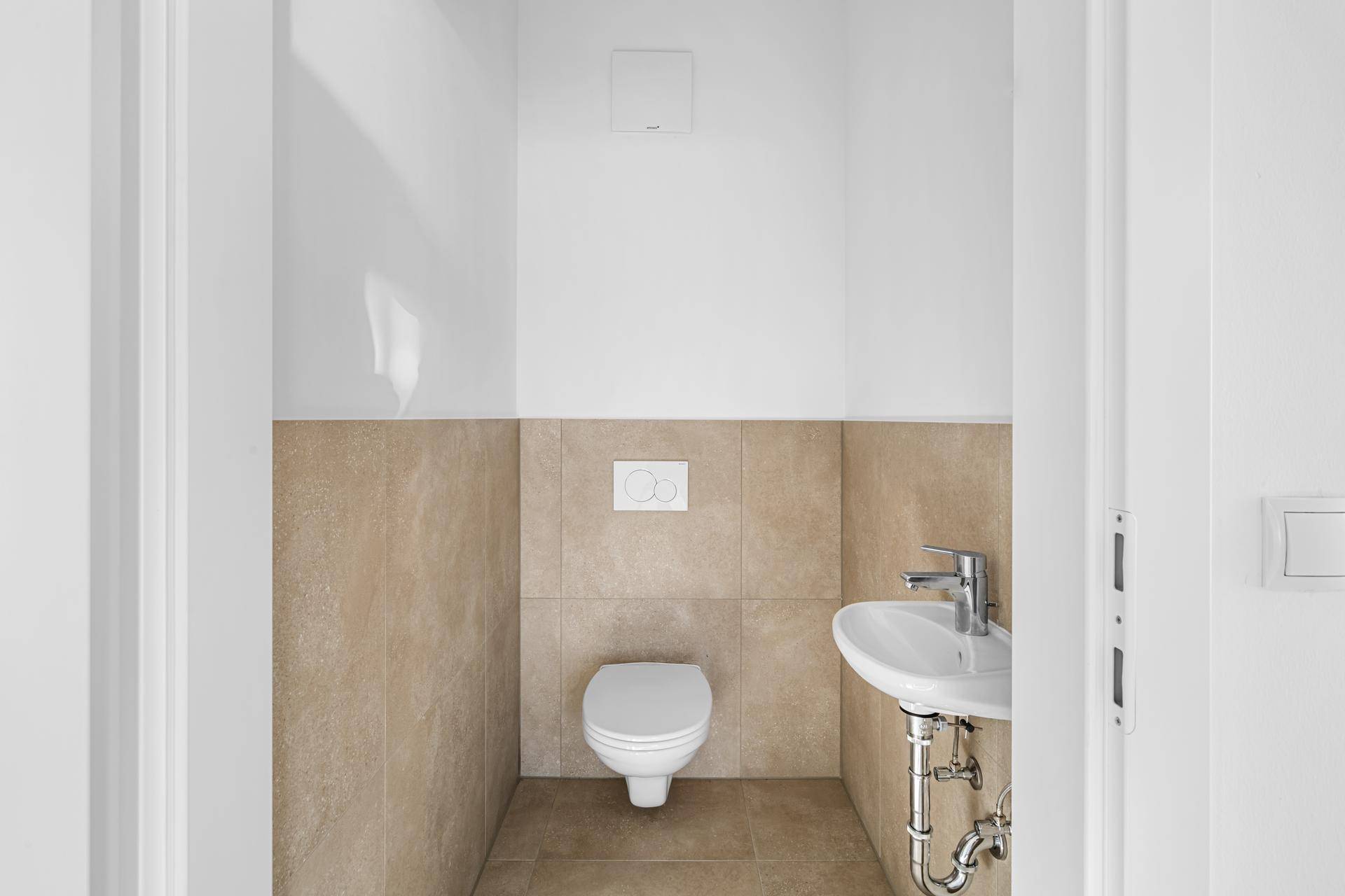 Modernes Gäste-WC mit Wand-WC und kleinem Waschtisch in hellem Design.