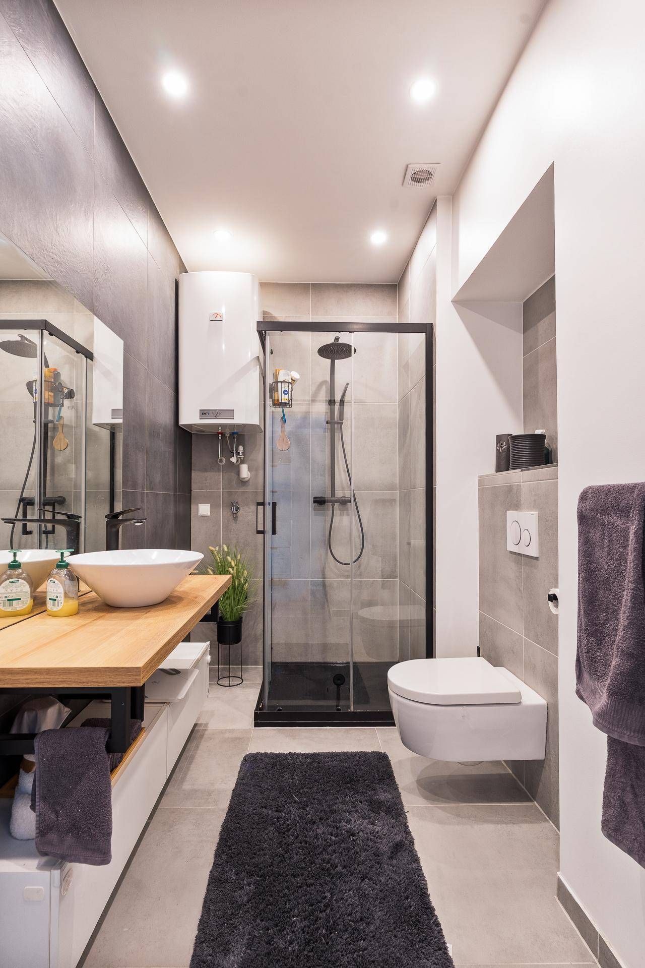 Modernes Badezimmer mit großer Duschkabine, Hänge-WC und Holzwaschtisch.