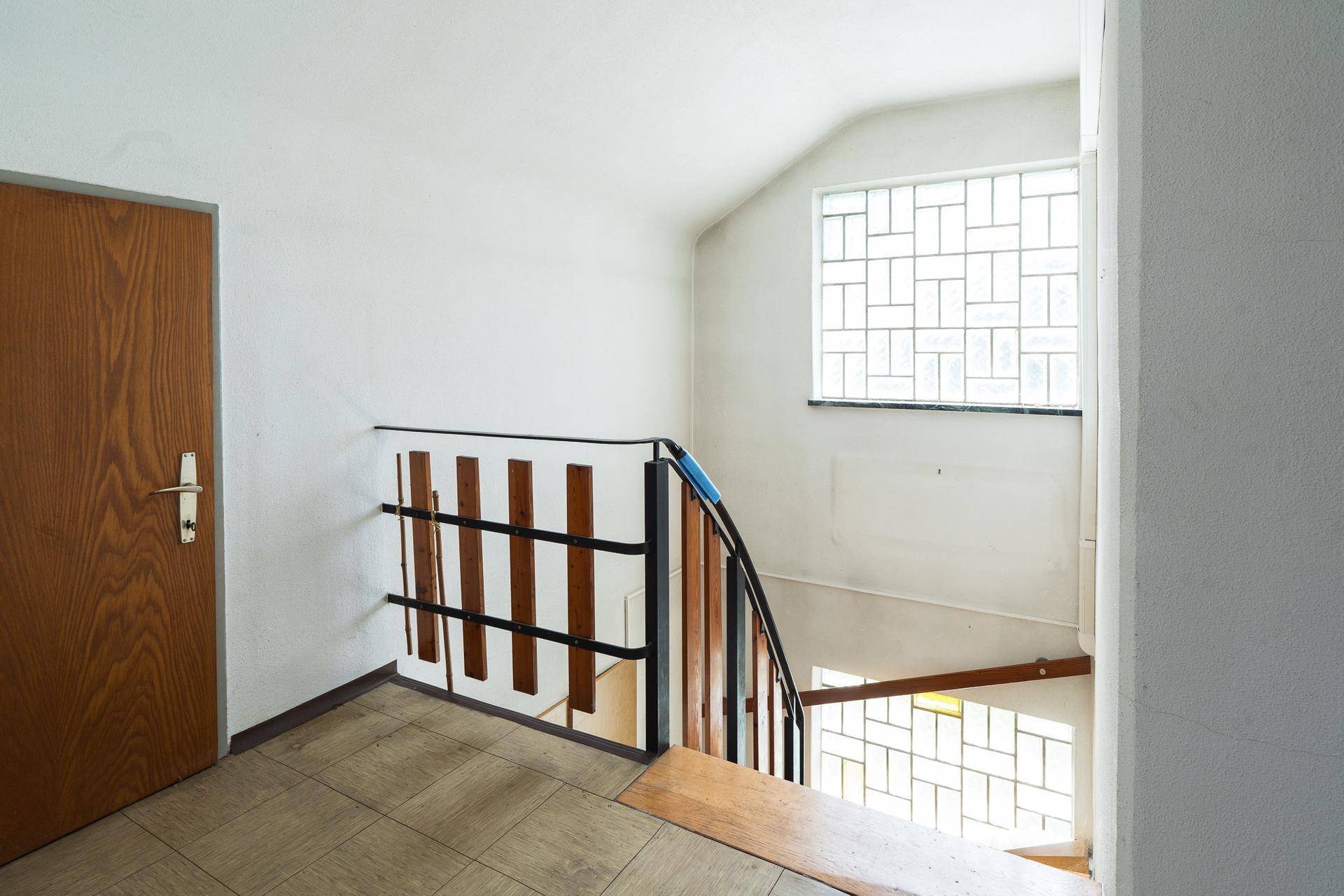 Treppenhaus mit dekorativem Fenster und Blick auf die untere Etage.