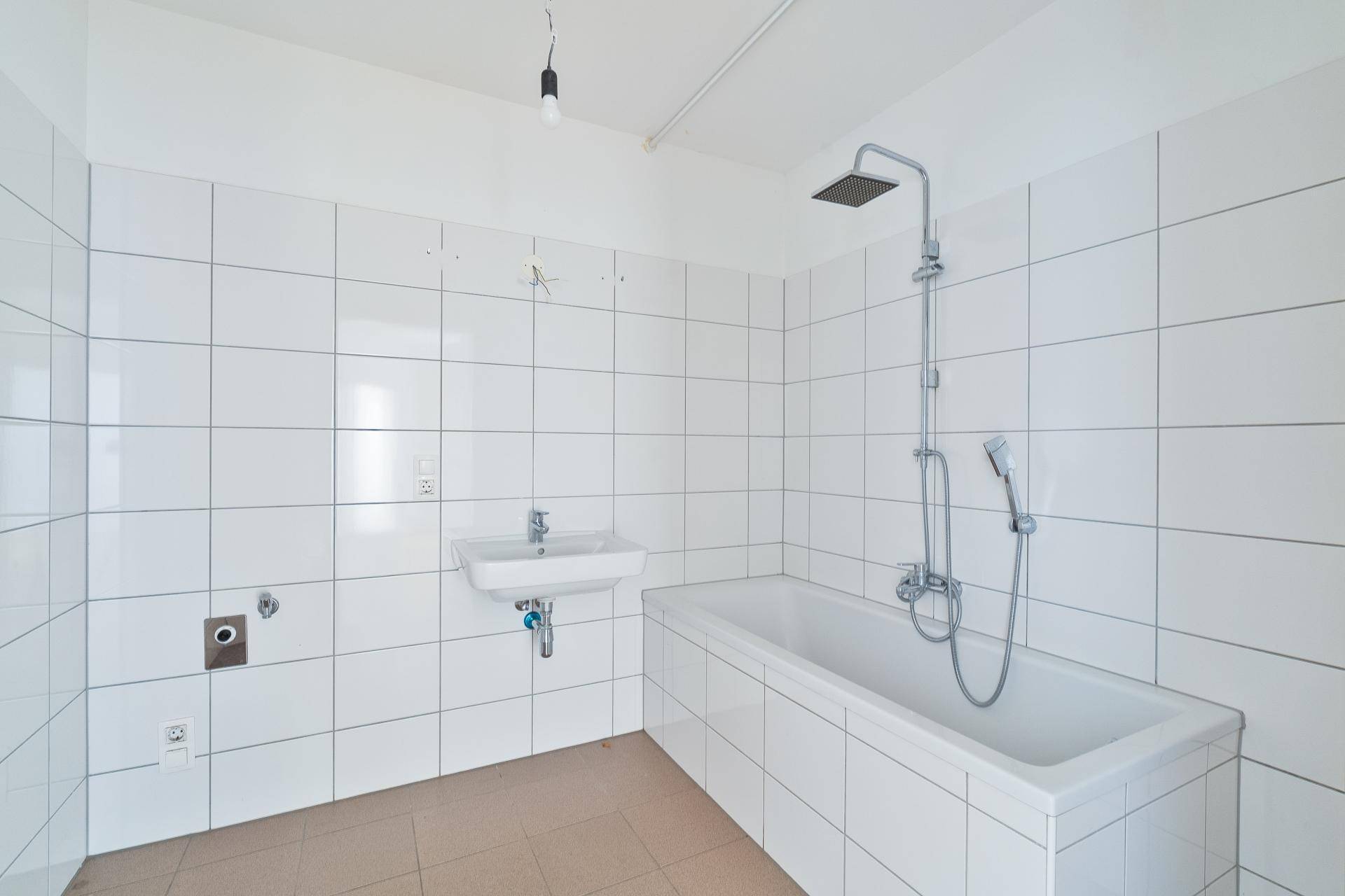 Gefliestes Badezimmer mit Badewanne, Duscharmatur und Waschbecken, in gutem Zustand.