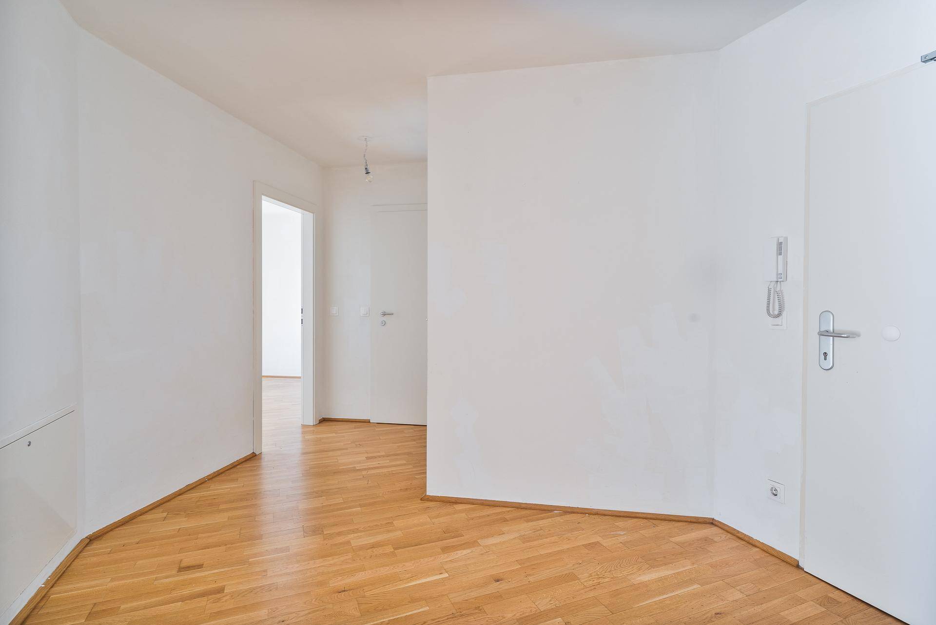 Heller Flurbereich mit Parkettboden und Zugang zu verschiedenen Zimmern der Wohnung.