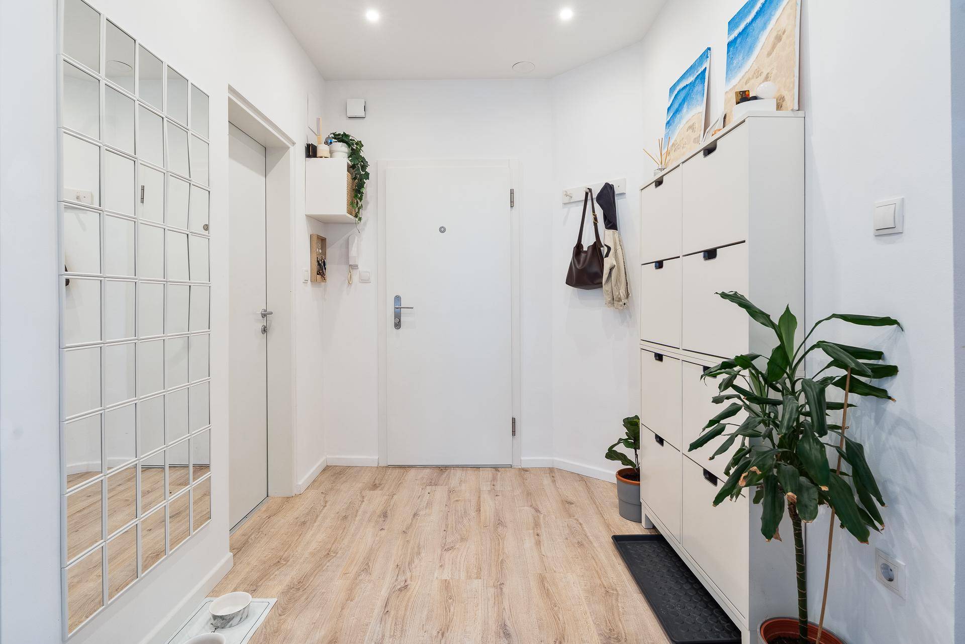 Heller Eingangsbereich mit Schuhschrank, großem Spiegel und Holzboden.