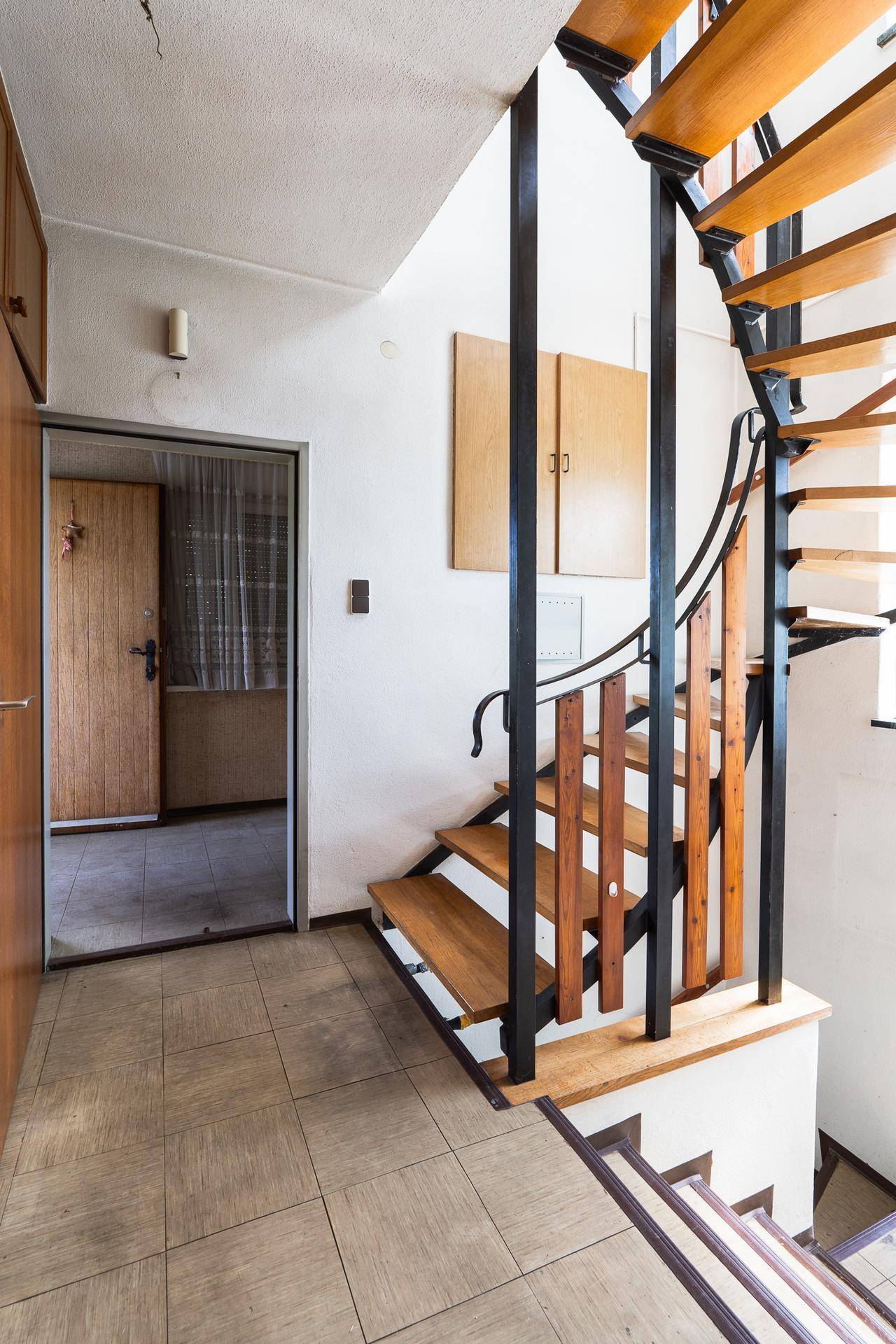 Heller Treppenabsatz mit Holzstufen und Zugang zu weiteren Räumen.