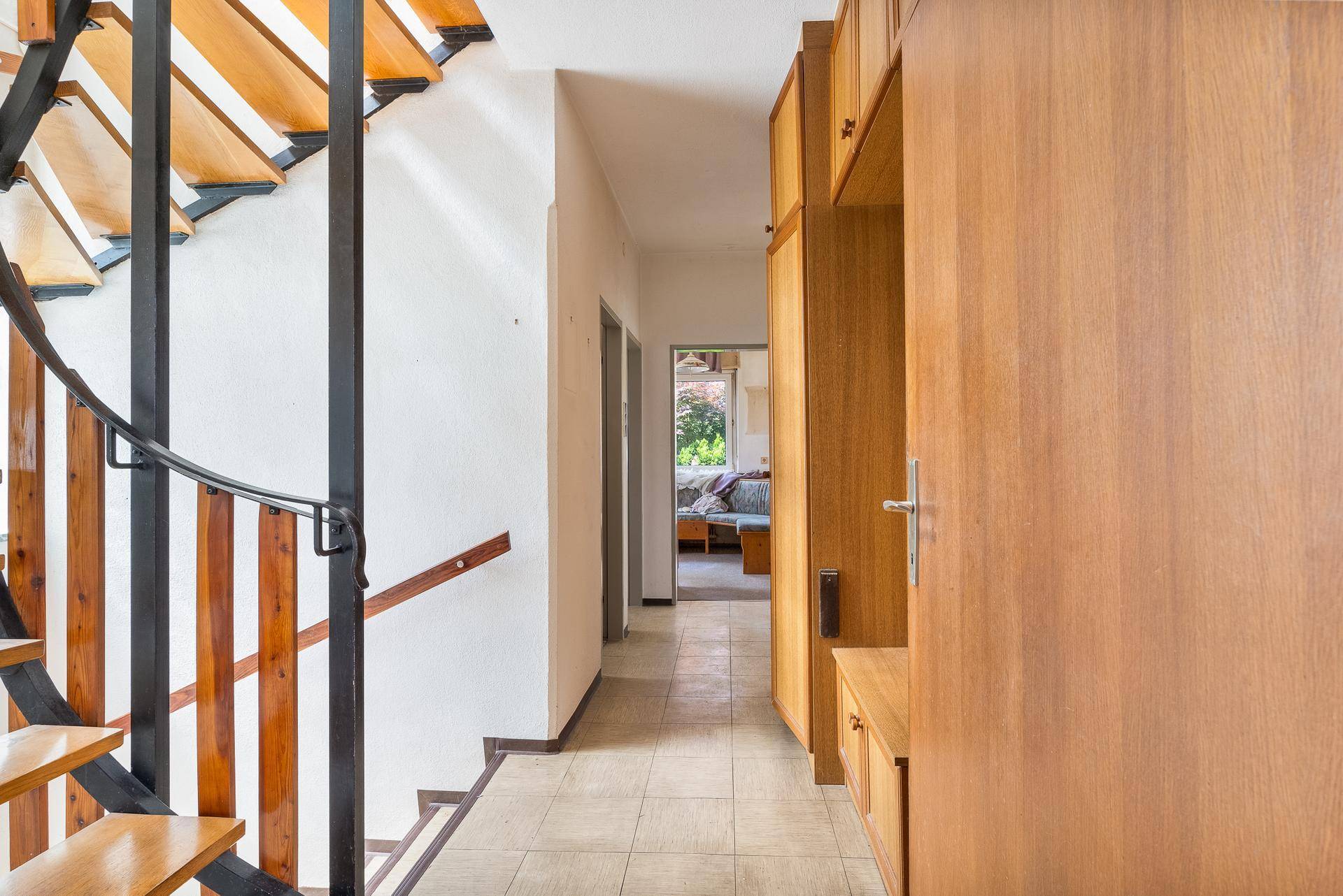 Heller Flur mit Wendeltreppe und Blick in einen angrenzenden Wohnbereich.