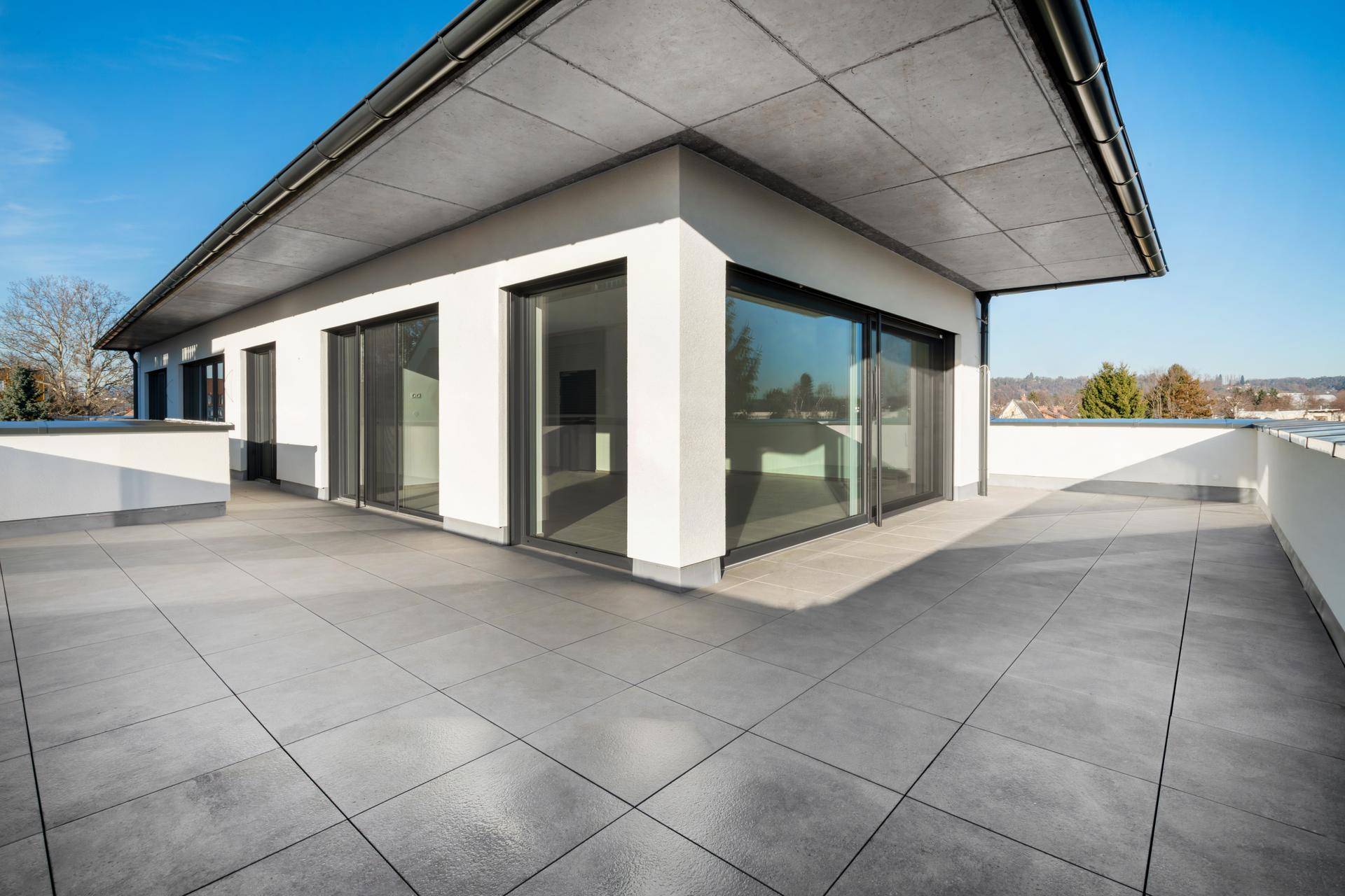 Moderne Architektur mit weitläufiger Dachterrasse und großen Fensterfronten für viel Licht.
