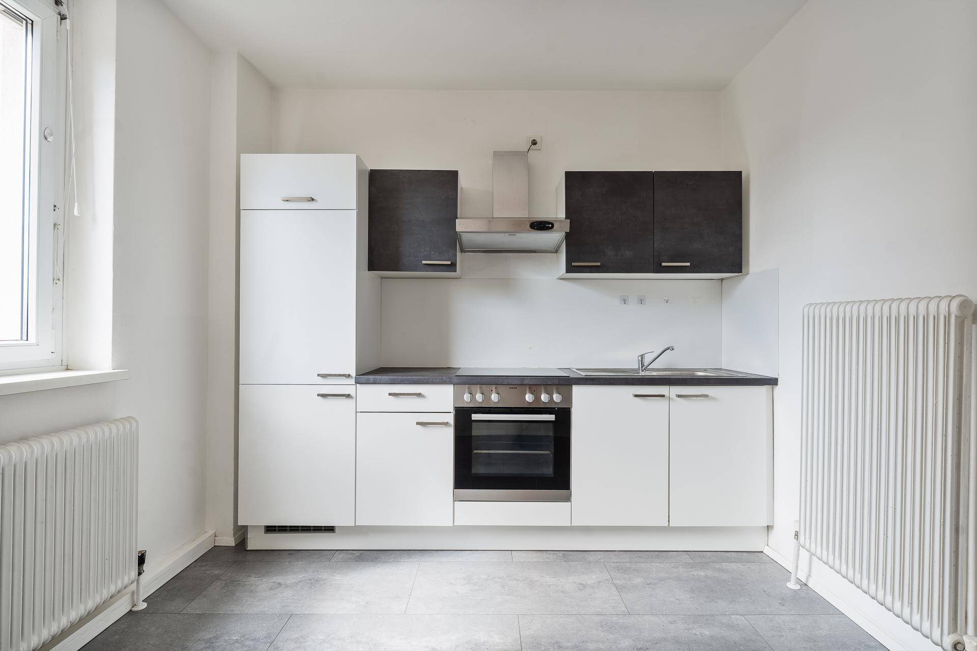 Moderne Einbauküche mit weißen und grauen Schränken sowie integrierten Geräten.