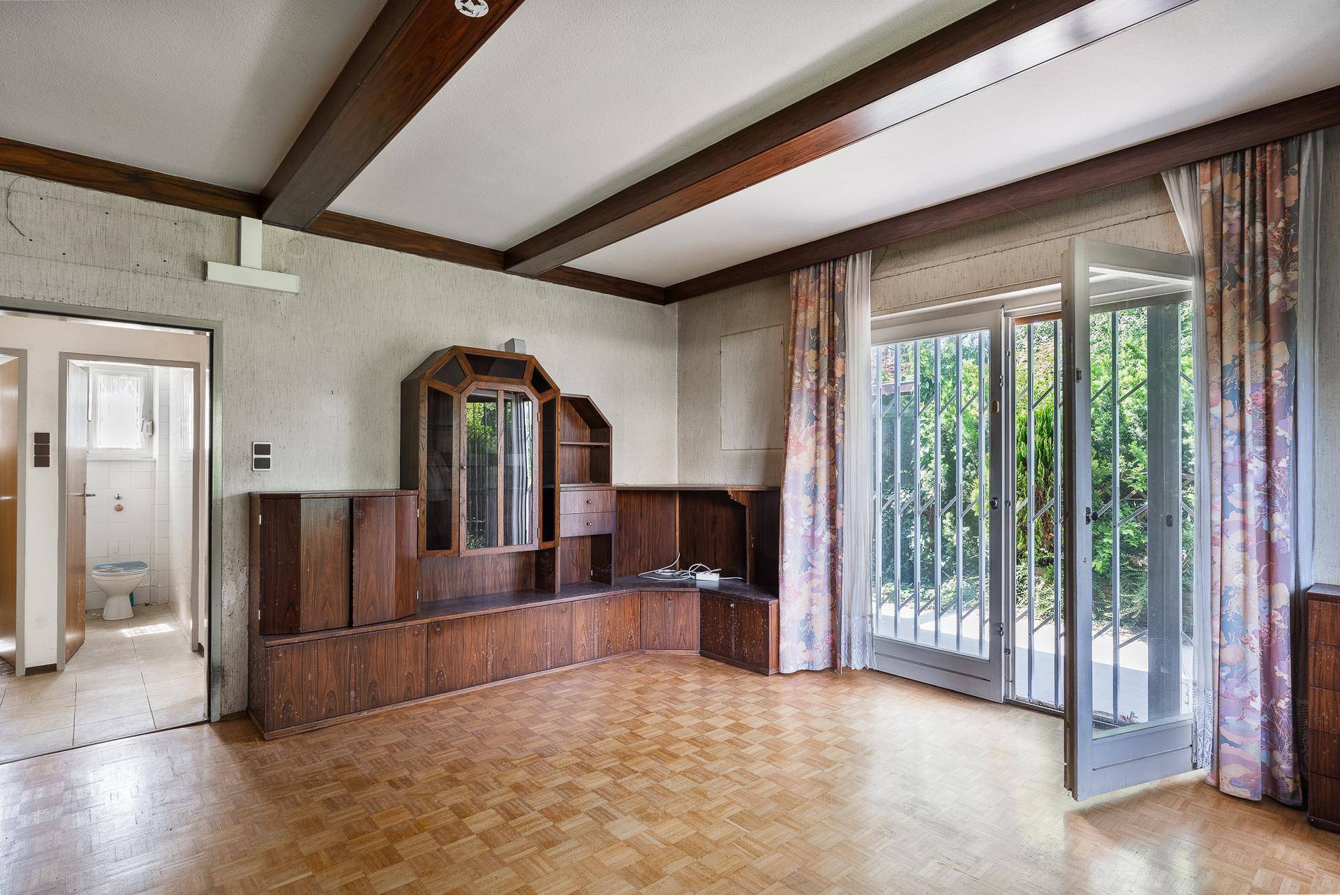 Wohnzimmer mit Zugang zur Terrasse und Blick in ein angrenzendes Badezimmer.