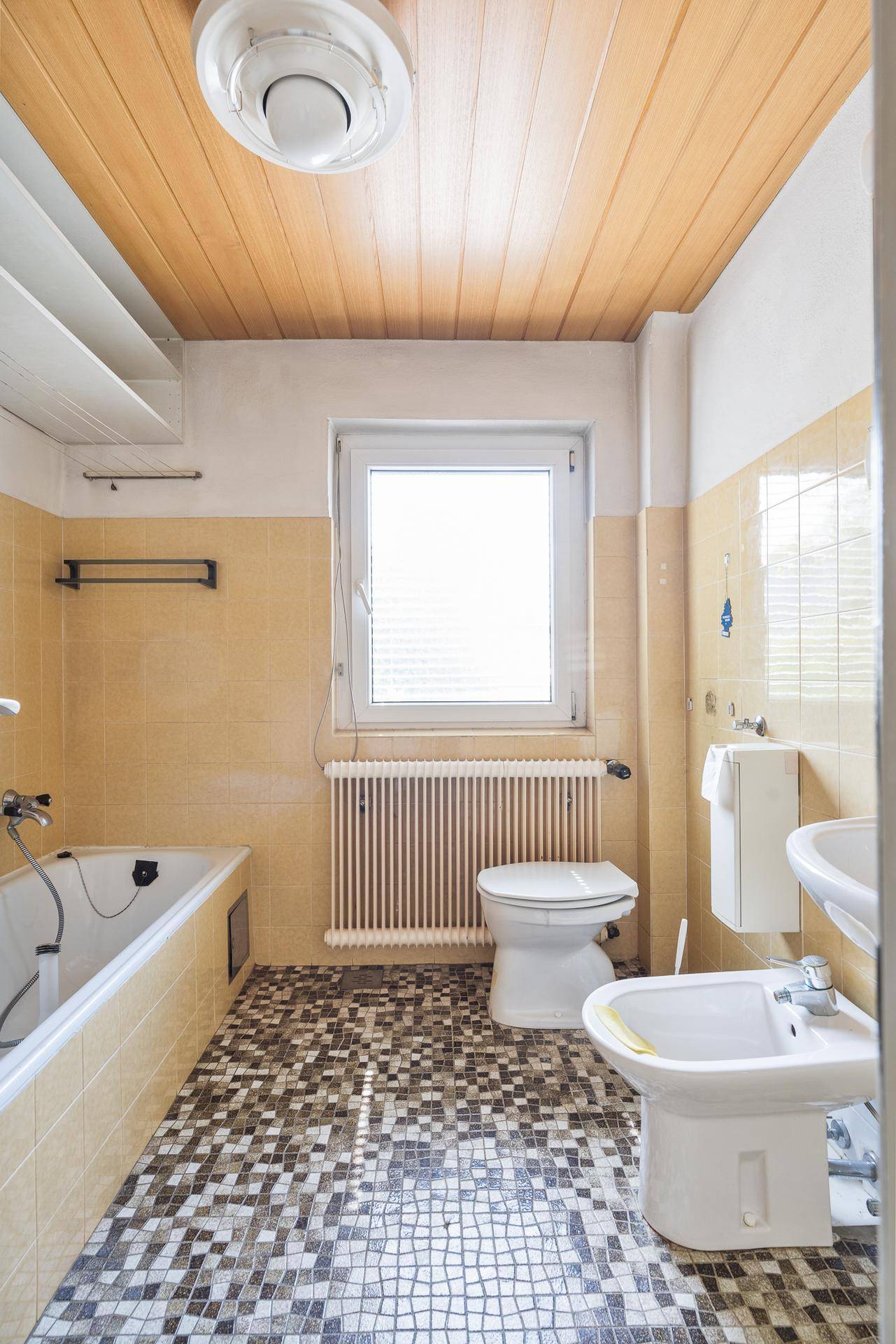 Badezimmer mit Badewanne, Bidet, WC und gemusterten Bodenfliesen.