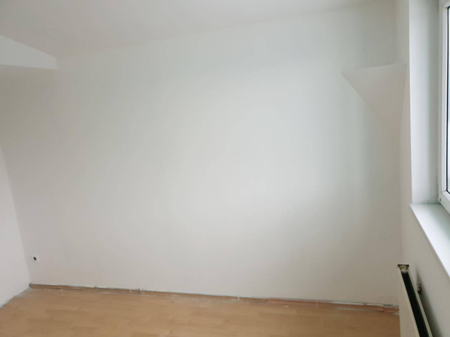 Leerer Raum mit weißen Wänden, Dachschräge, Fenster und Holzboden, bereit zur individuellen Gestaltung.