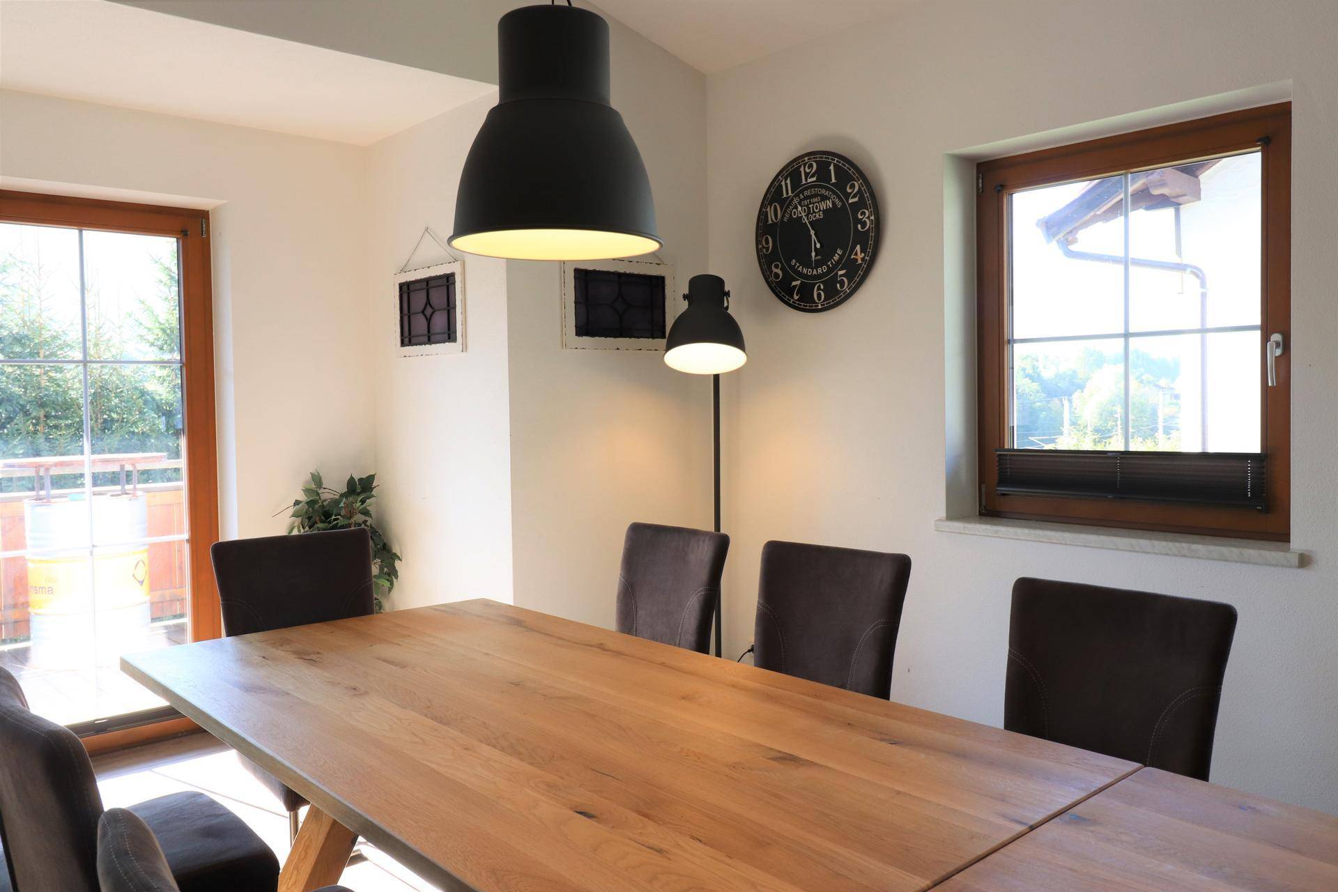 Heller Essbereich mit großem Holztisch, dunklen Stühlen und direktem Zugang zum Balkon.
