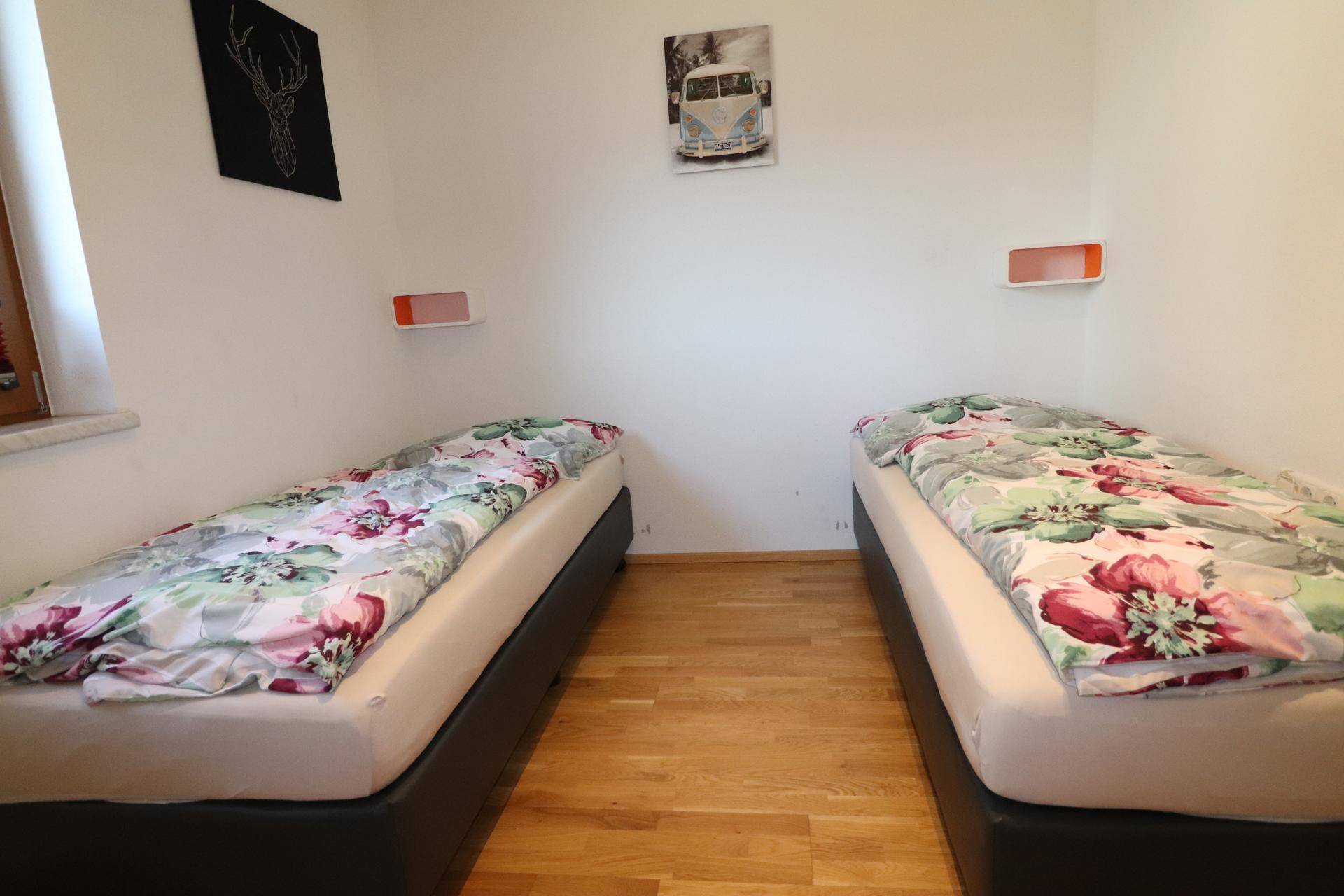 Schlafzimmer mit zwei Einzelbetten, floraler Bettwäsche und hellem Holzboden.