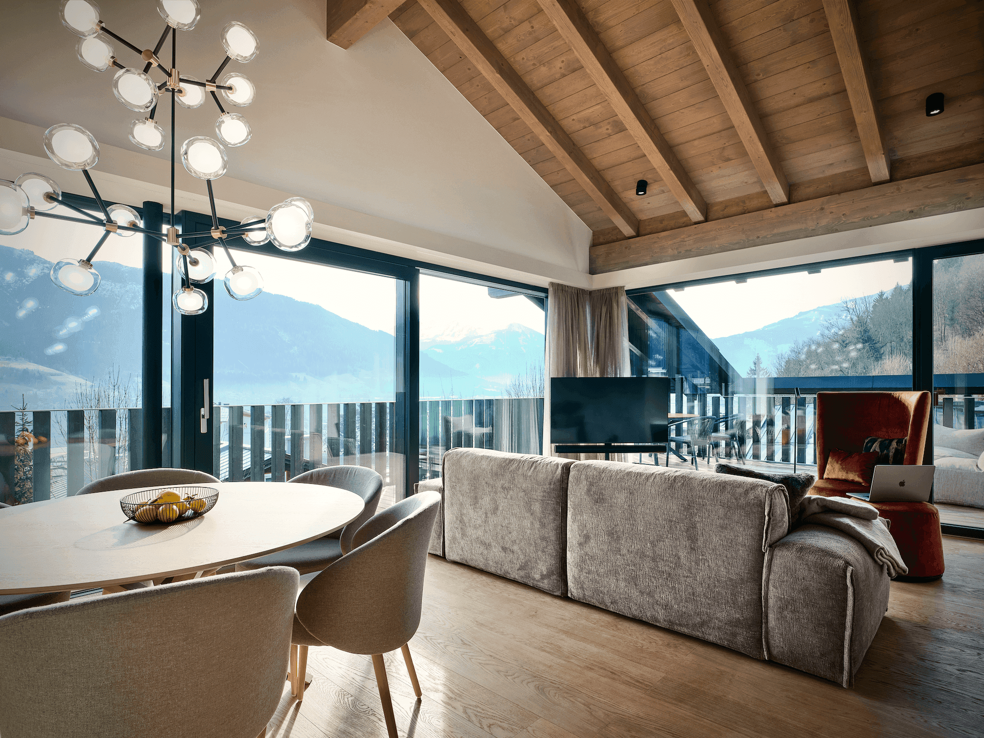 Offener Wohn-Essbereich mit gemütlichem Sofa, Esstisch und Panoramafenstern mit beeindruckendem Bergblick.