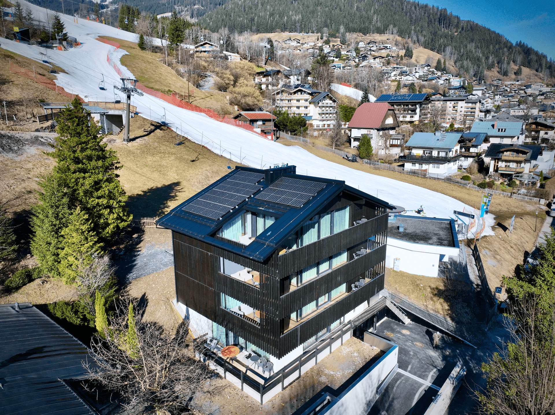 Das moderne Gebäude mit Solarpaneelen auf dem Dach liegt direkt an einer Skipiste in den Bergen.