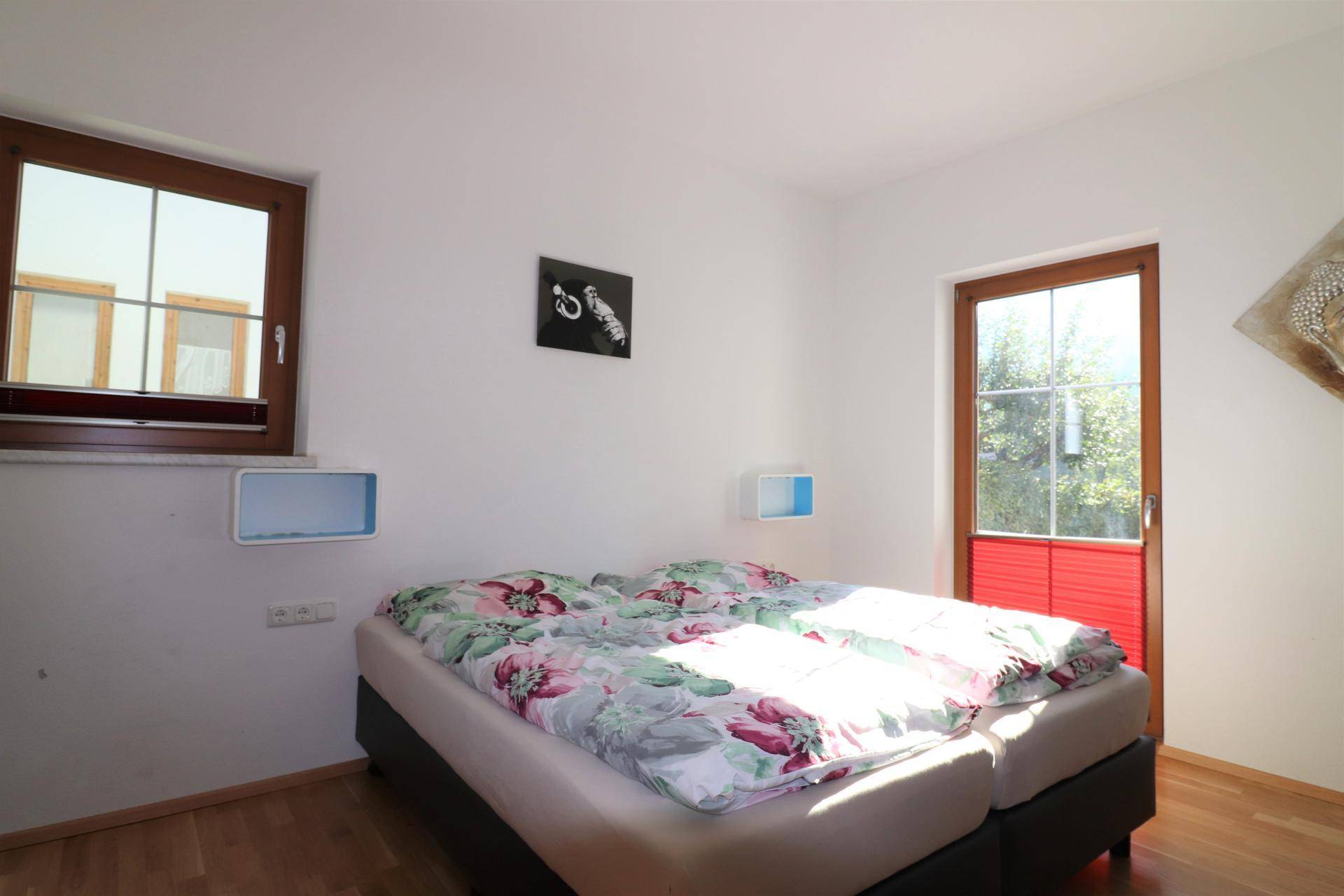 Helles Schlafzimmer mit Doppelbett, Holzboden und direktem Zugang zu einem Außenbereich.