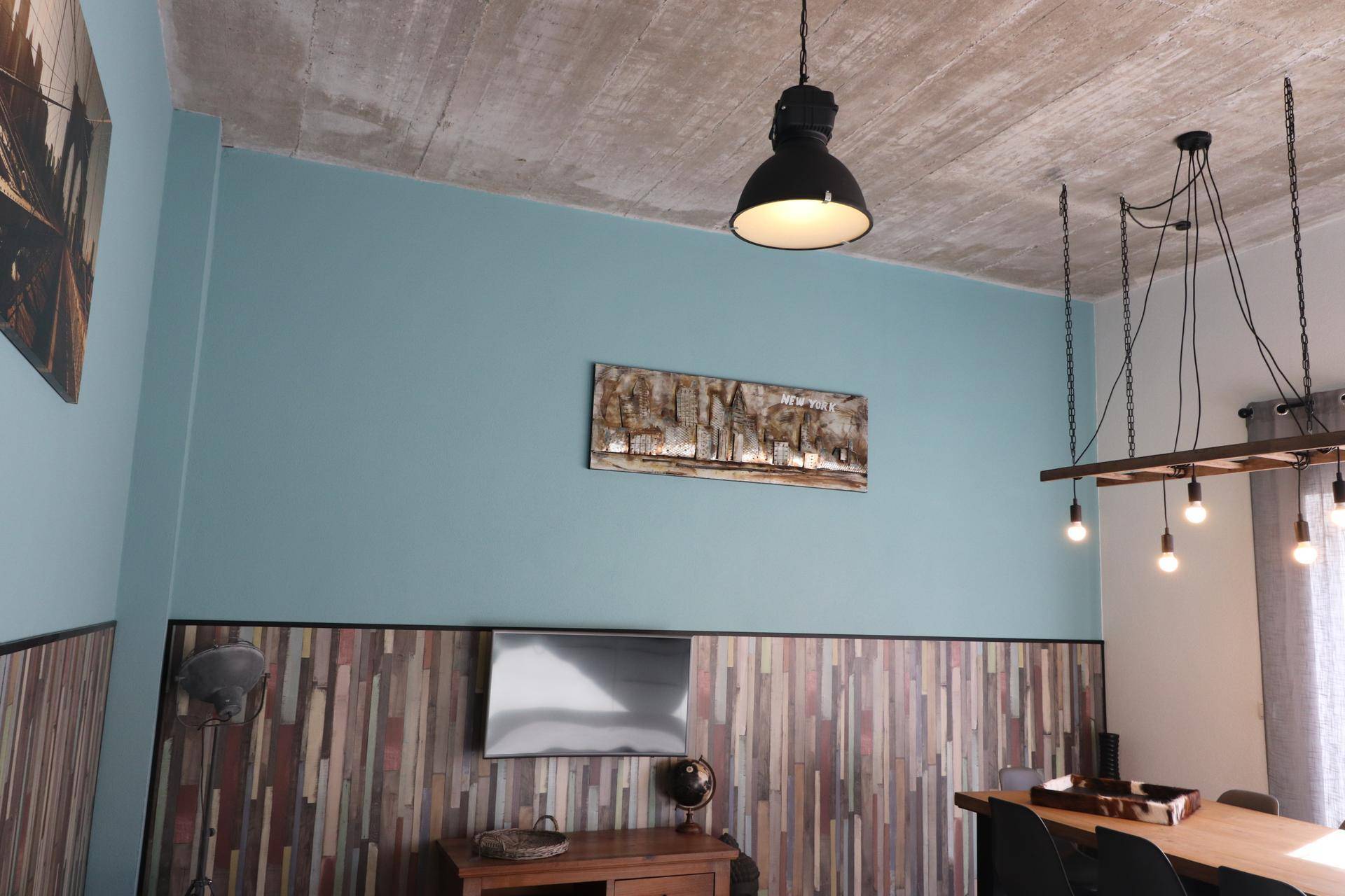 Detailansicht des Wohnbereichs mit Holzwandverkleidung, Kunstwerken und moderner Beleuchtung.