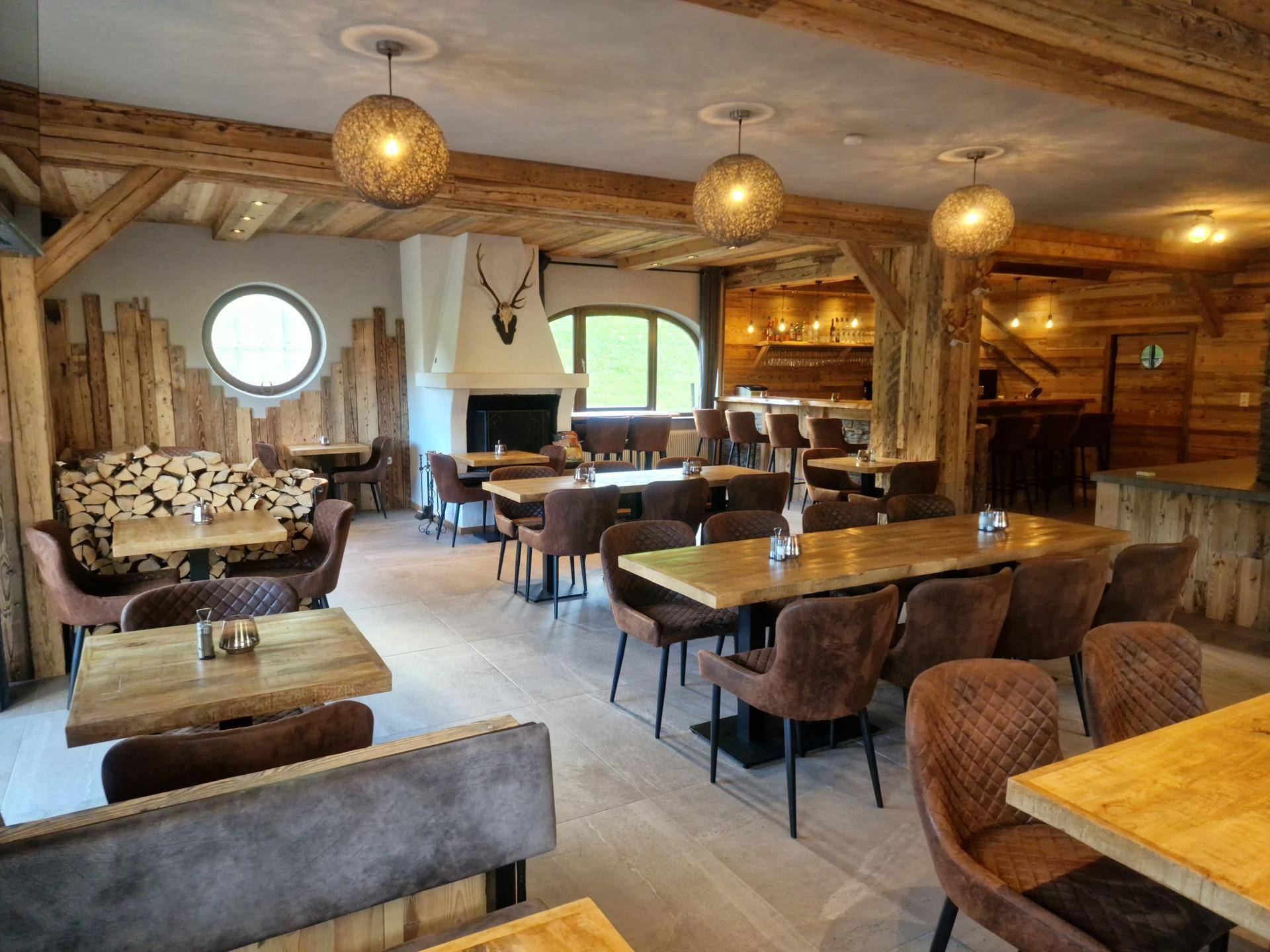 Rustikaler Speisesaal mit Holzbalken, Kamin und gemütlichen Tischen für Gäste.