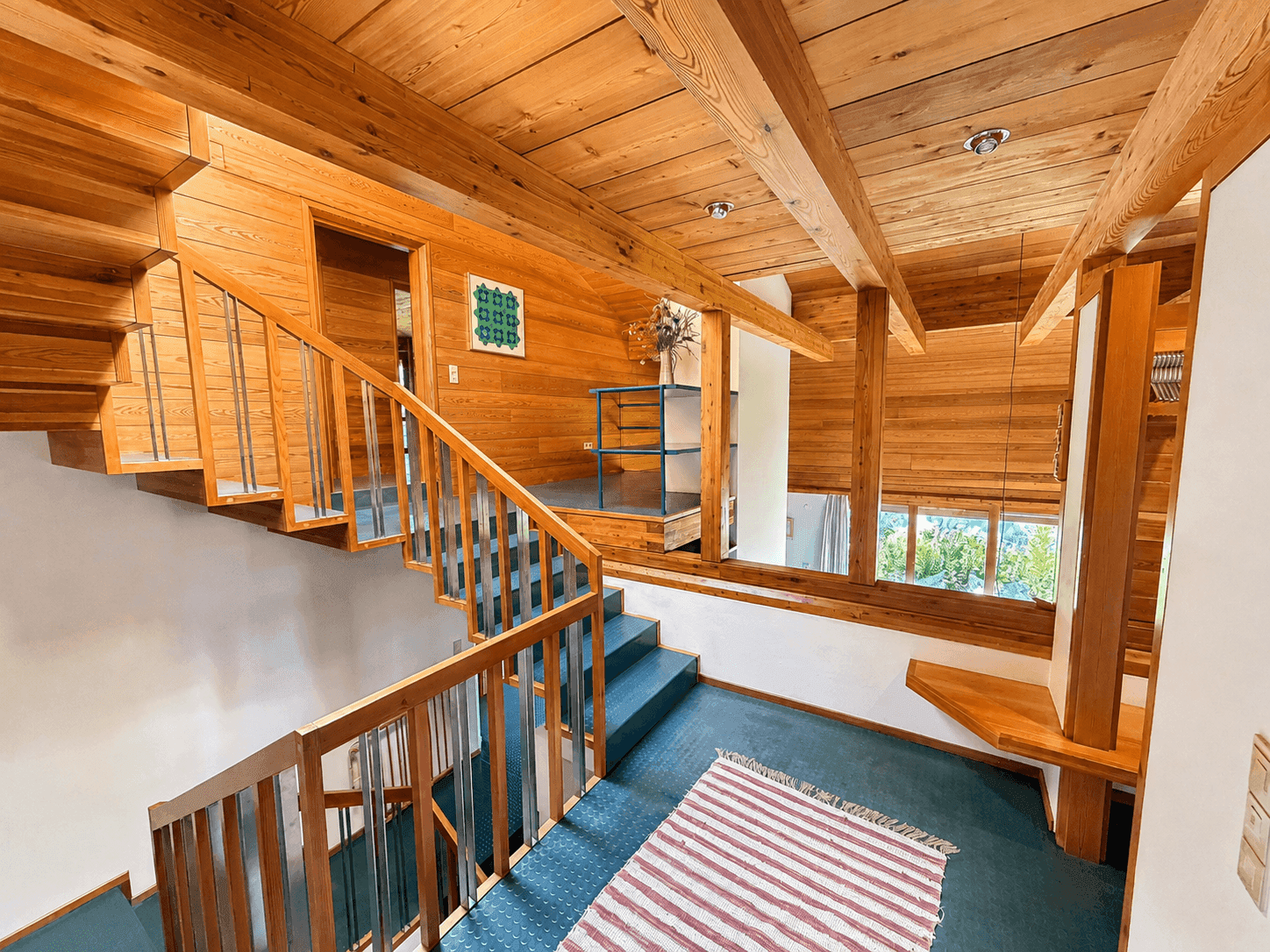 Geräumiger Flur mit Holztreppe, Holzbalkendecke und Blick auf die Umgebung.