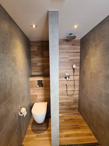 Modernes Badezimmer mit begehbarer Dusche, Wand-WC und Holzoptik-Fliesen.