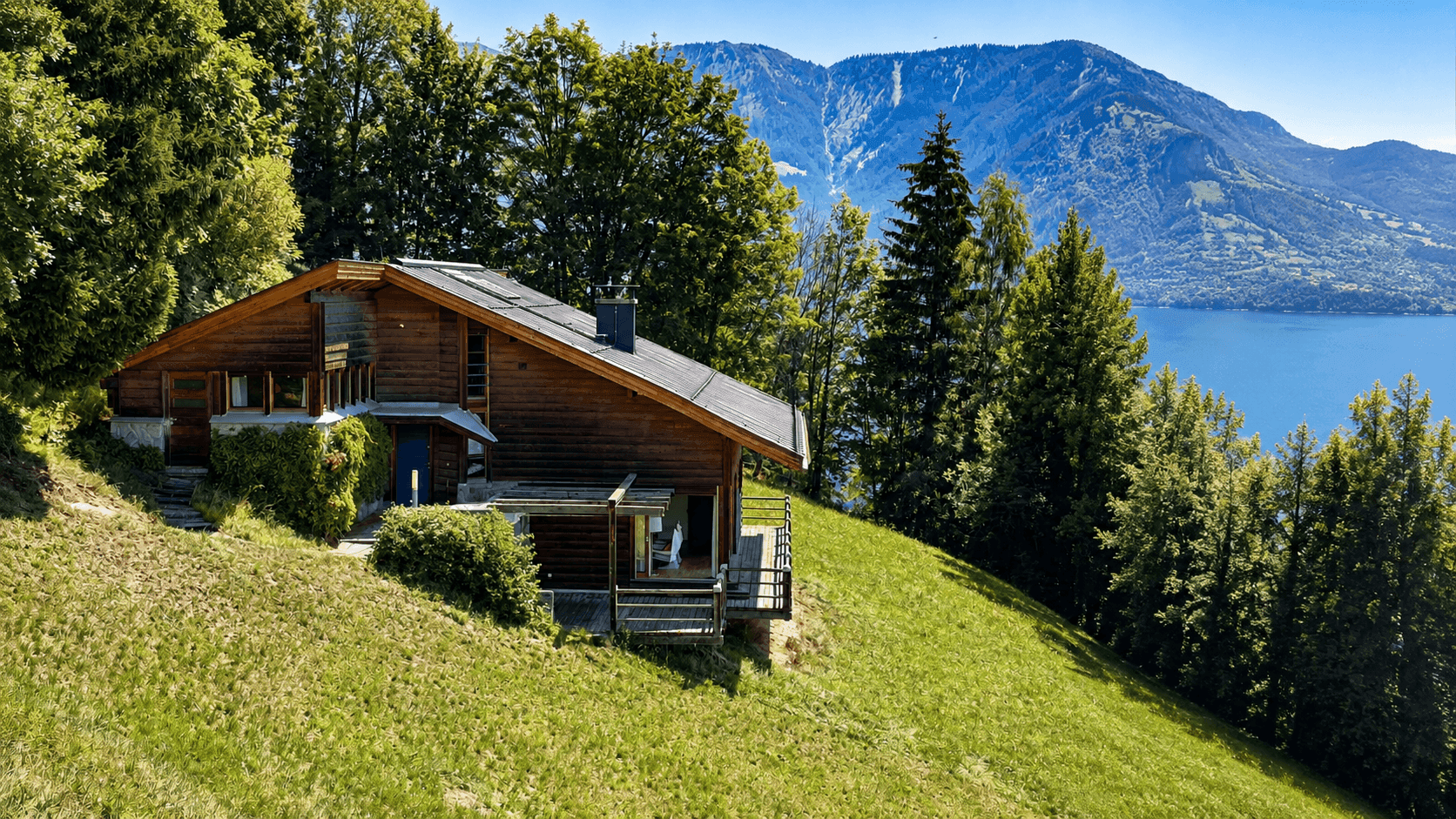 Charmantes Holzhaus mit Seeblick und Bergblick, eingebettet in eine grüne Hügellandschaft.