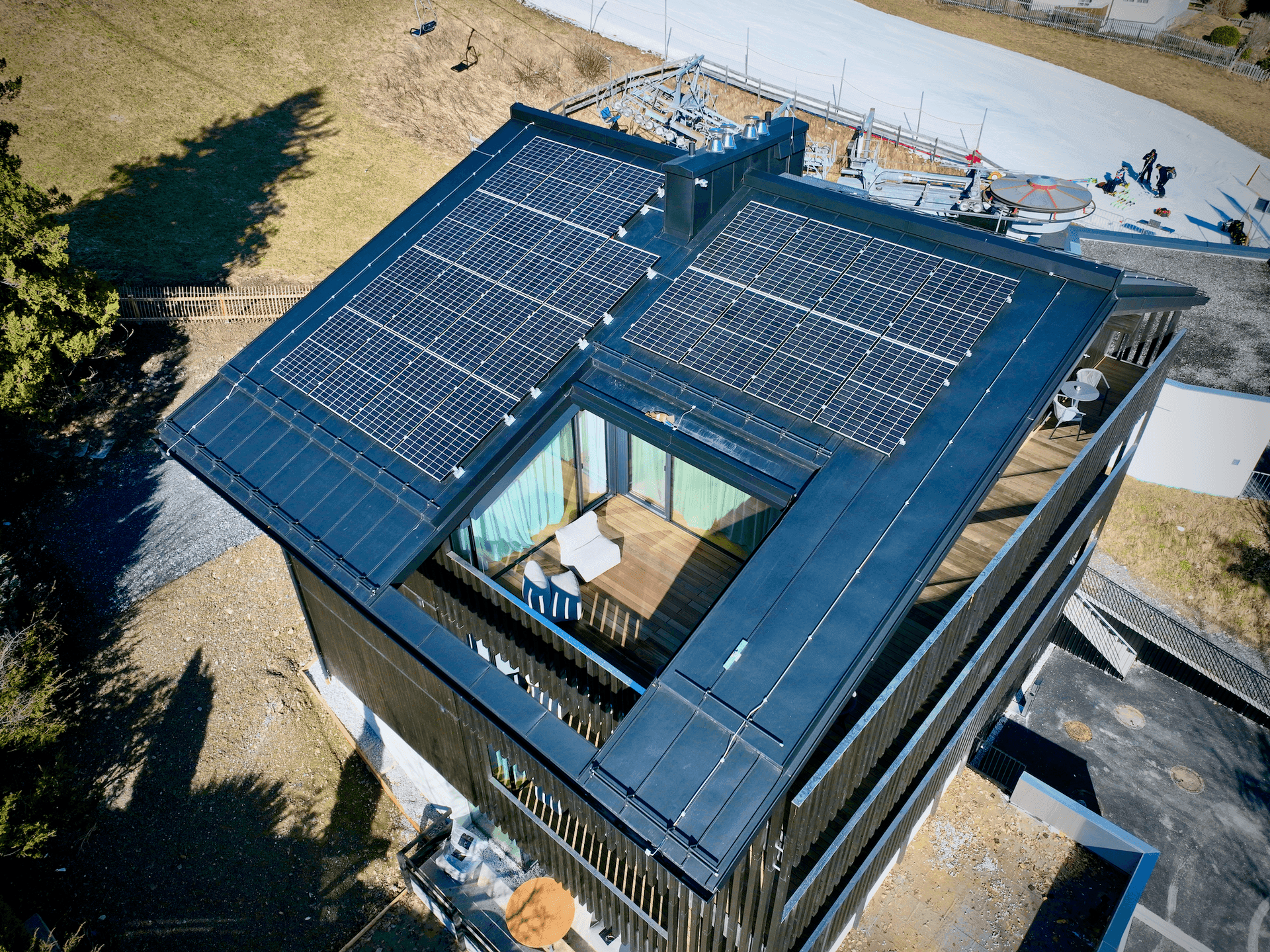 Dachansicht des Gebäudes mit Solarpaneelen und einer möblierten Loggia im oberen Bereich.