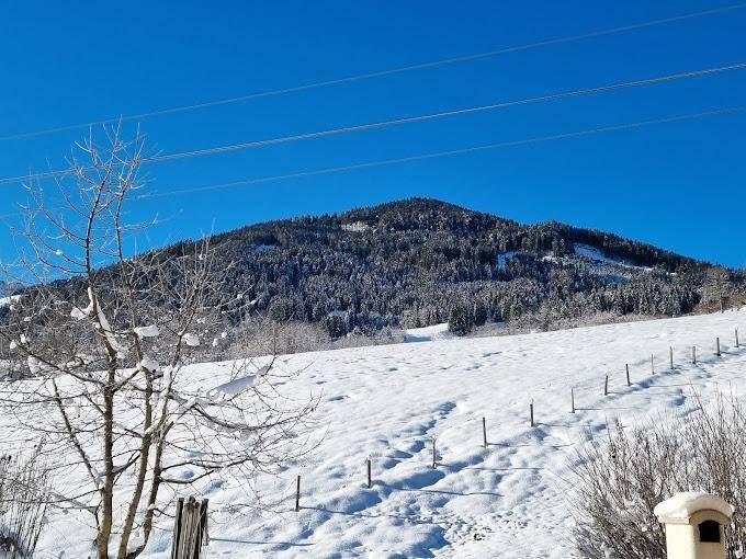 Weitläufige, schneebedeckte Berglandschaft unter strahlend blauem Himmel im Winter.