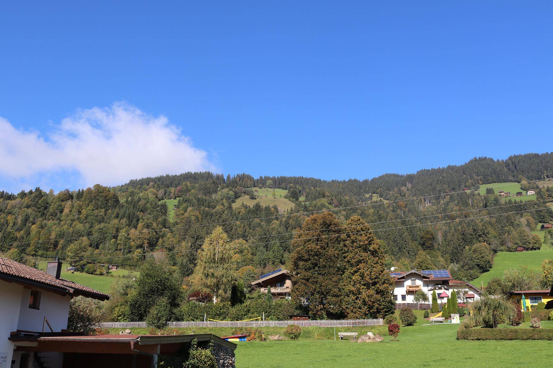 Malerische Landschaft mit grünen Hügeln, Wäldern und traditionellen Häusern.