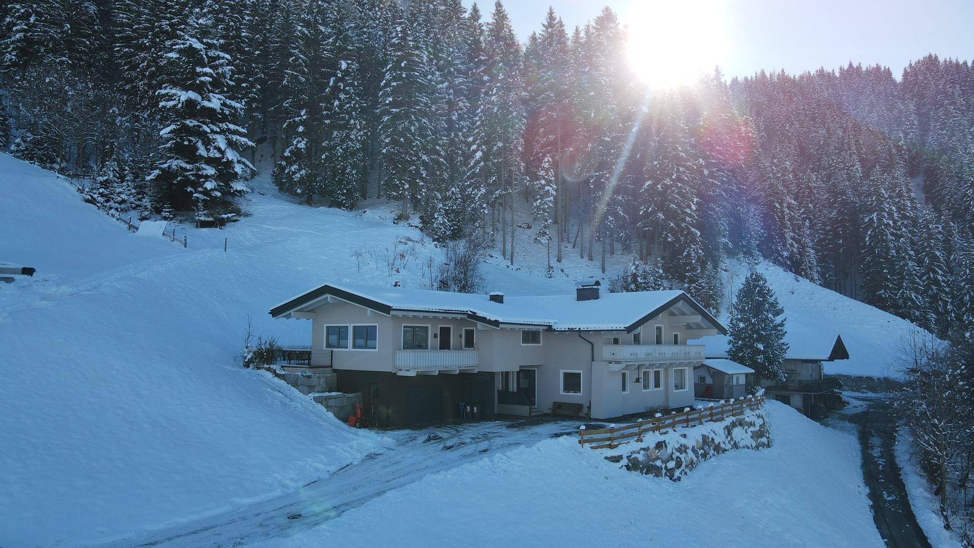 Winterliche Ansicht des Hauses mit verschneiten Bäumen und strahlendem Sonnenschein.