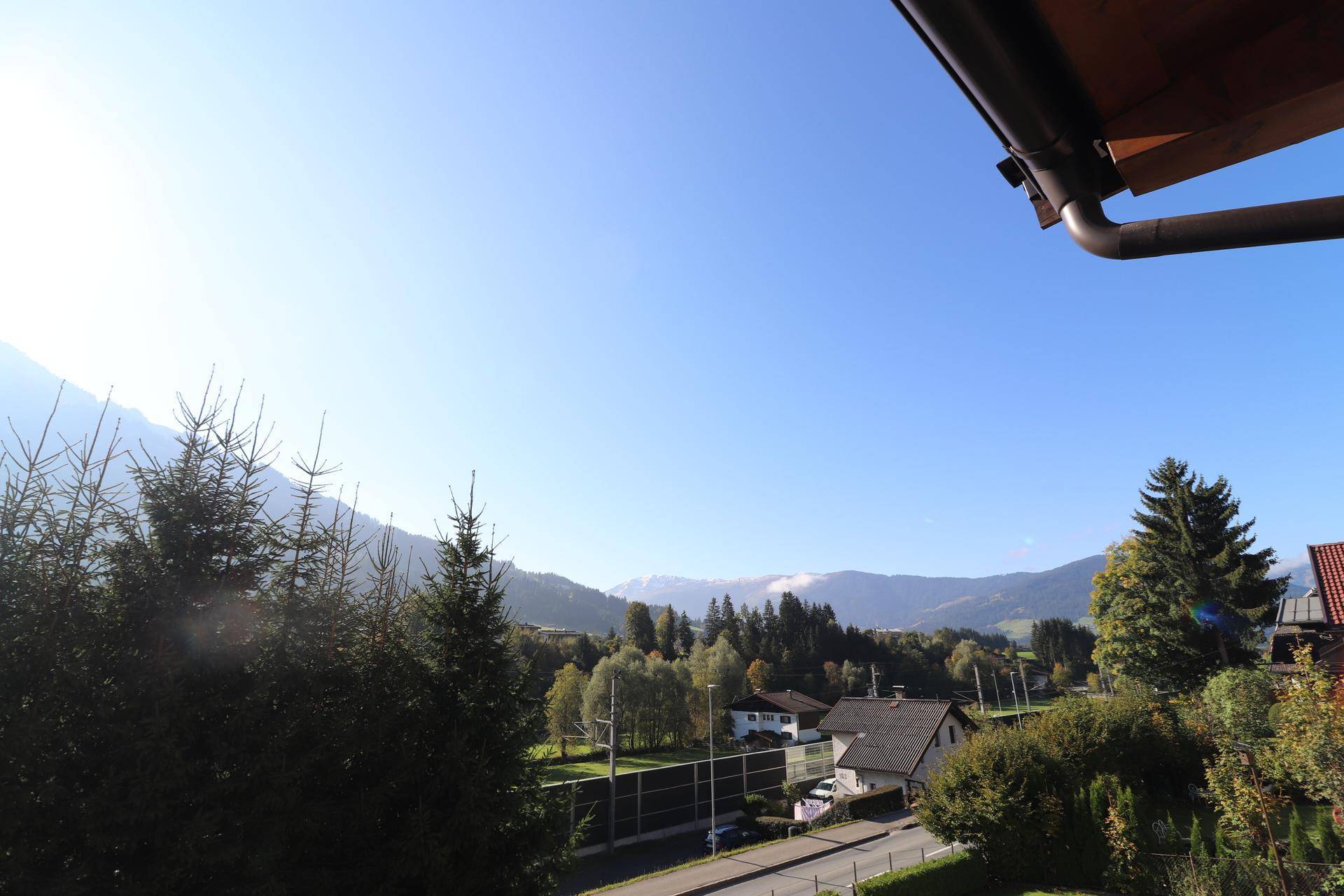 Weitläufiger Blick auf die umliegende Berglandschaft und grüne Täler unter blauem Himmel.