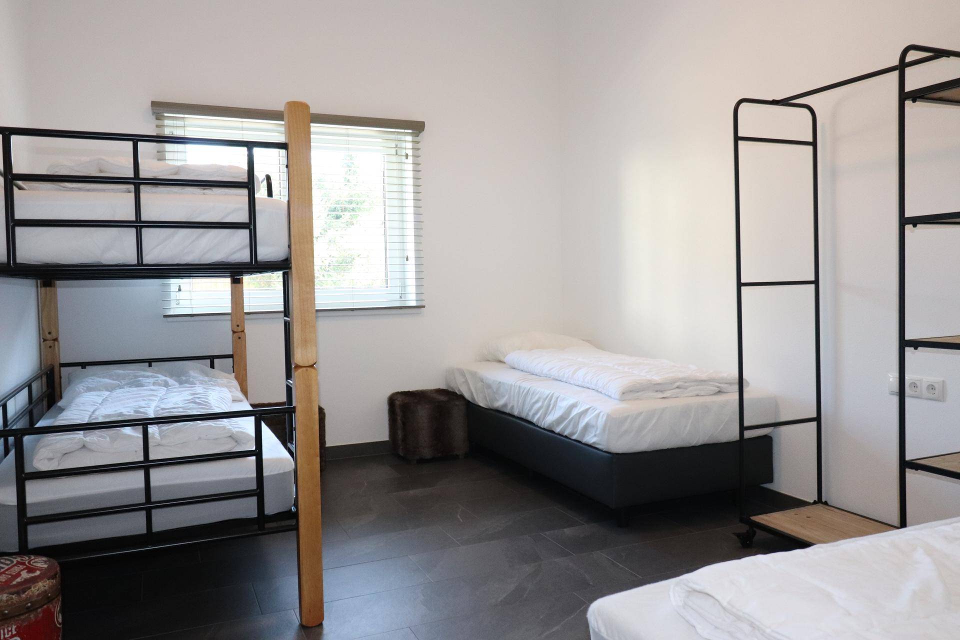 Helles Schlafzimmer mit Etagenbett und Einzelbetten, ideal für Gäste oder Kinder.