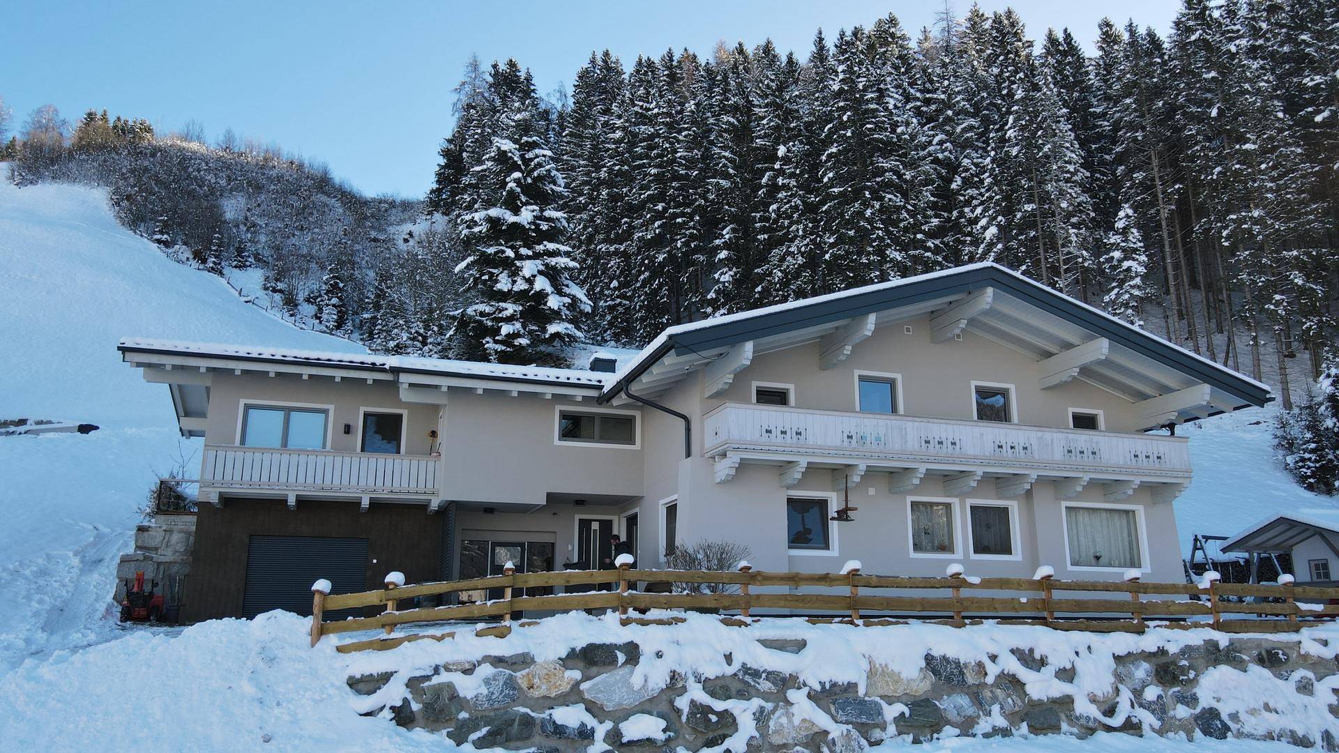 Nahaufnahme der Hausfassade mit traditionellem Balkon und schneebedeckter Umgebung.