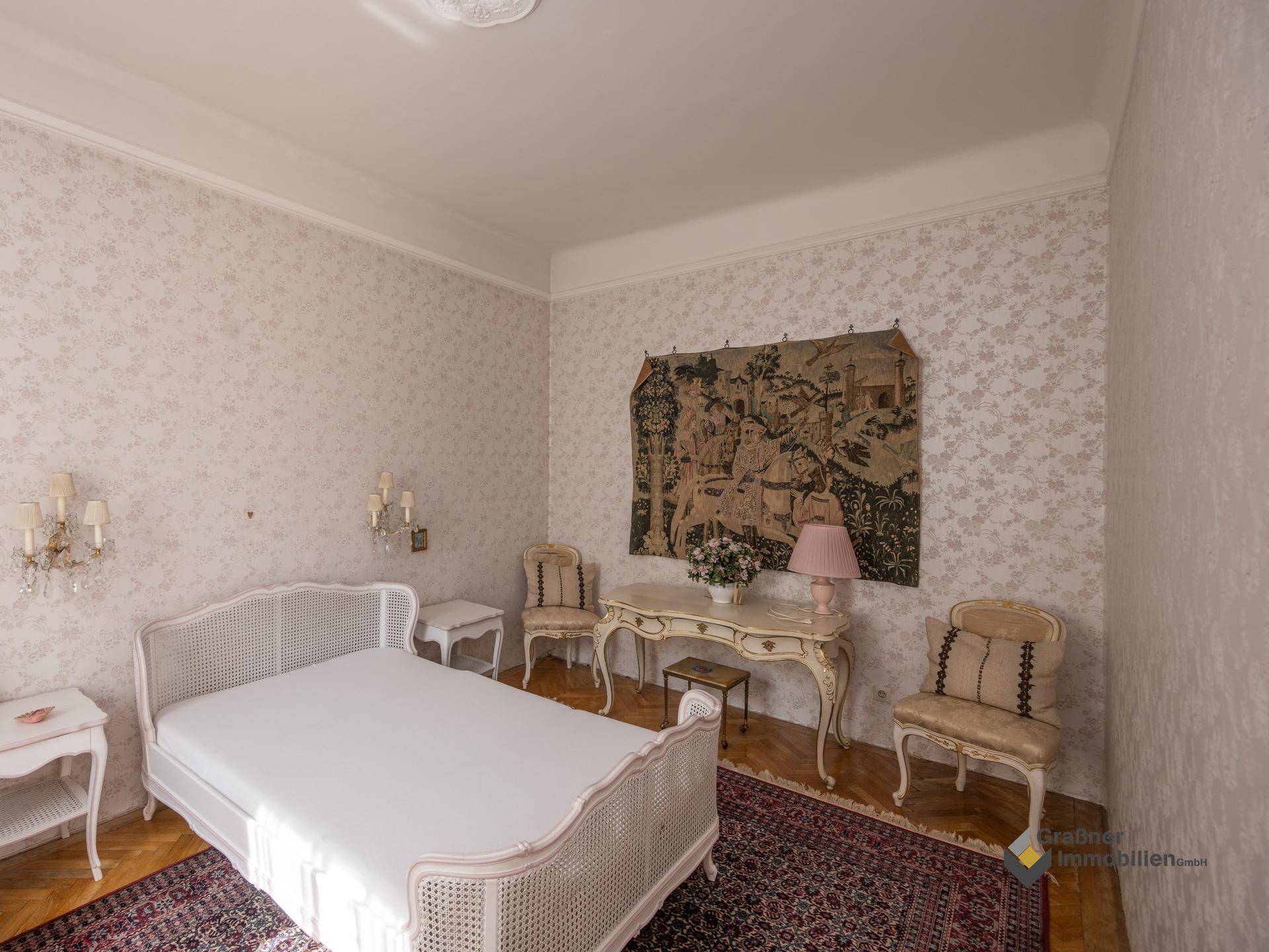 Helles Schlafzimmer mit eleganten Möbeln, Parkettboden und dekorativer Wandtapete.