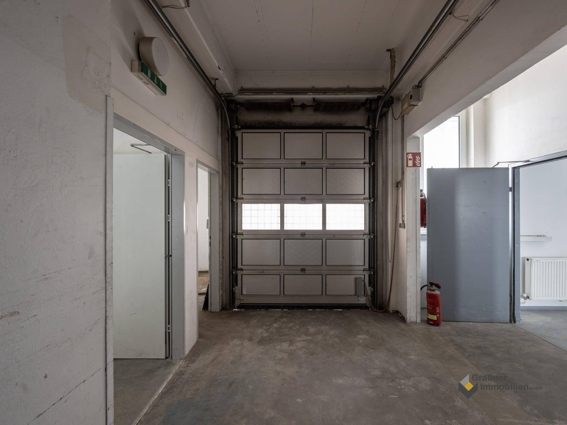 Weiterer Blick in den Industrieraum mit geschlossenem Rolltor und Betonboden.