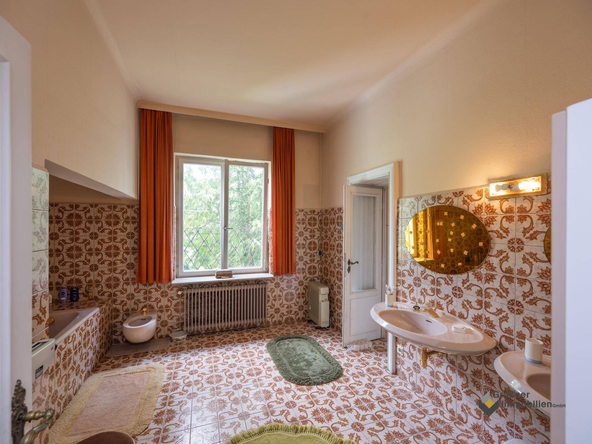 Geräumiges Badezimmer mit Fenster, Badewanne, Bidet und auffälligen Fliesen im Vintage-Stil.