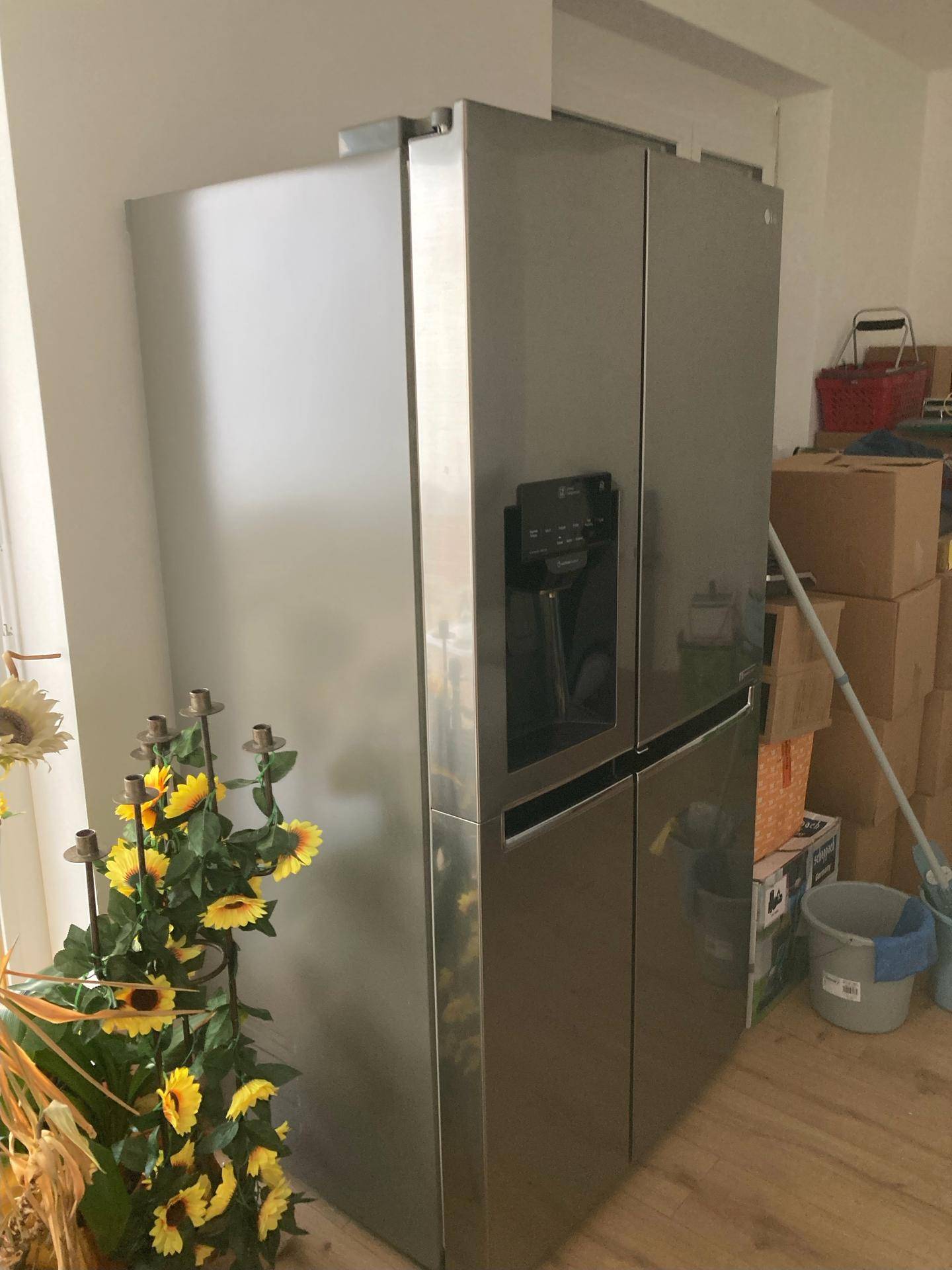 Großer, moderner Kühlschrank aus Edelstahl mit Wasserspender in einem hellen Raum.