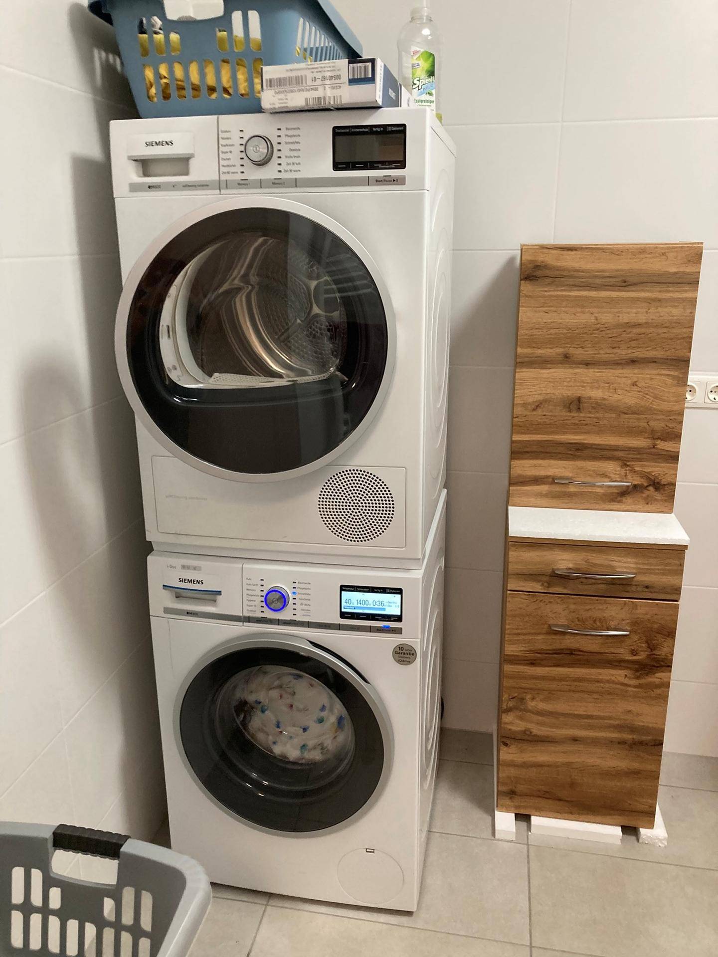 Waschküche mit gestapelter Waschmaschine und Trockner von Siemens sowie Holzschrank.