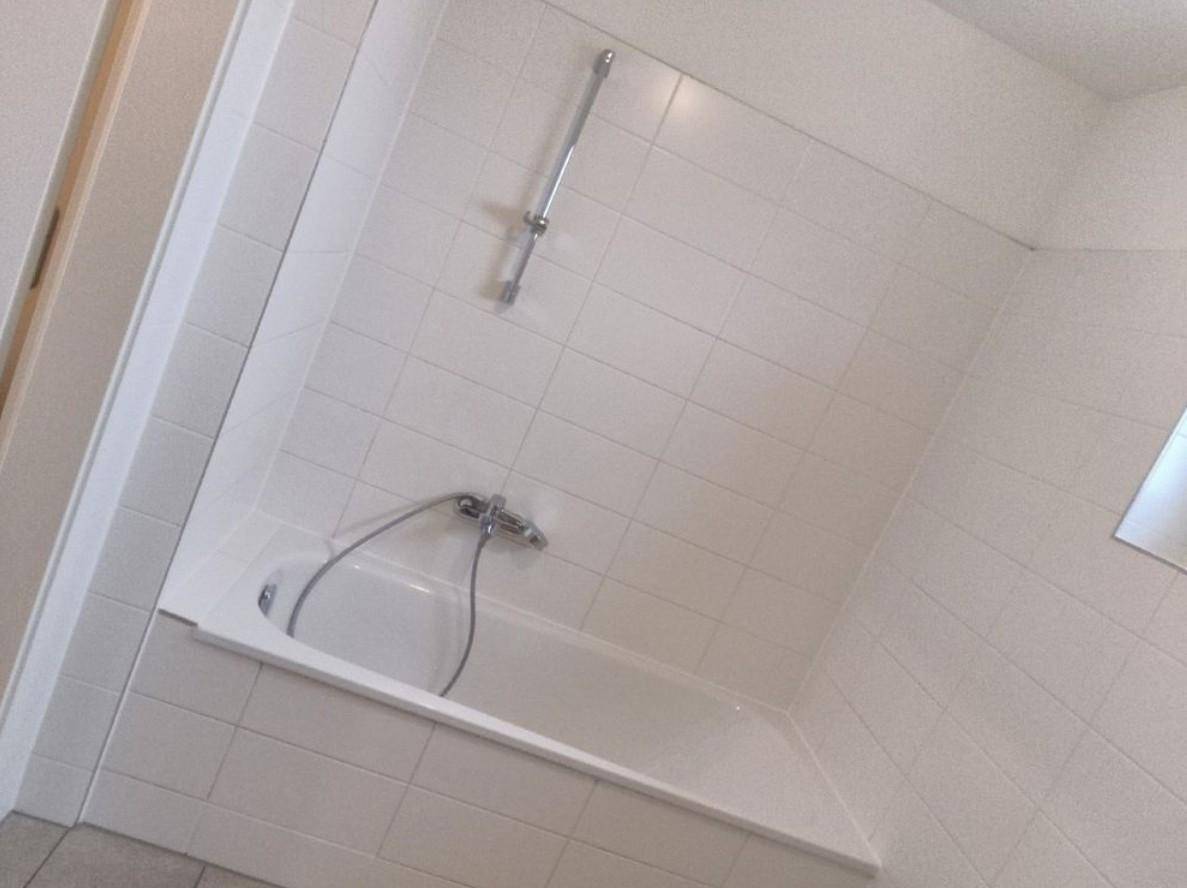 Modernes Badezimmer mit weißen Fliesen und einer integrierten Badewanne.