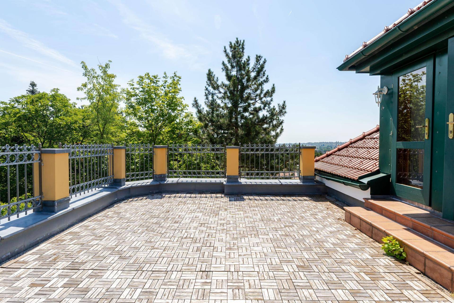 Weitläufige Dachterrasse mit Holzbodenfliesen und Panoramablick auf die grüne Landschaft.