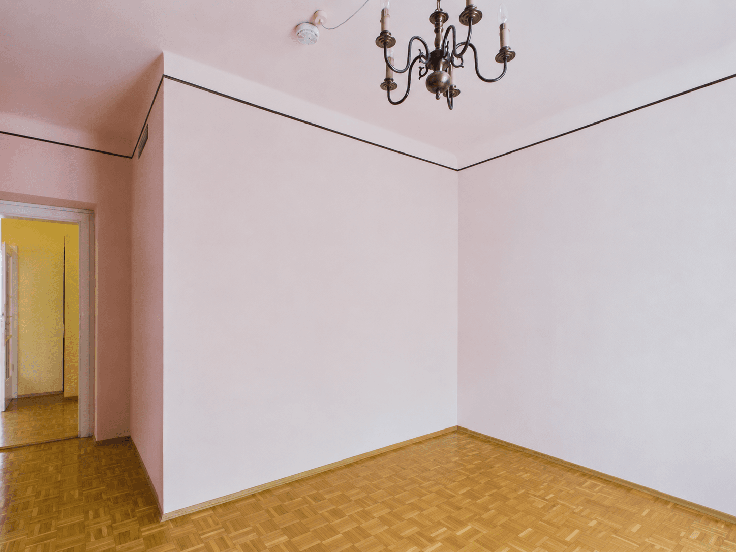 Heller Flur mit Parkettboden und Kronleuchter, der zu weiteren Räumen führt.