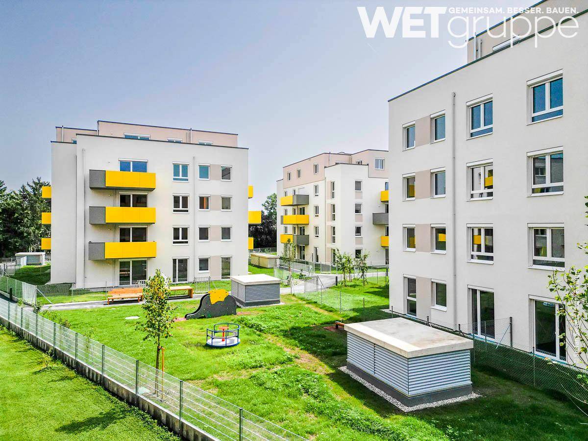Moderne Wohnanlage mit großzügigen Grünflächen und einem kleinen Spielplatz.