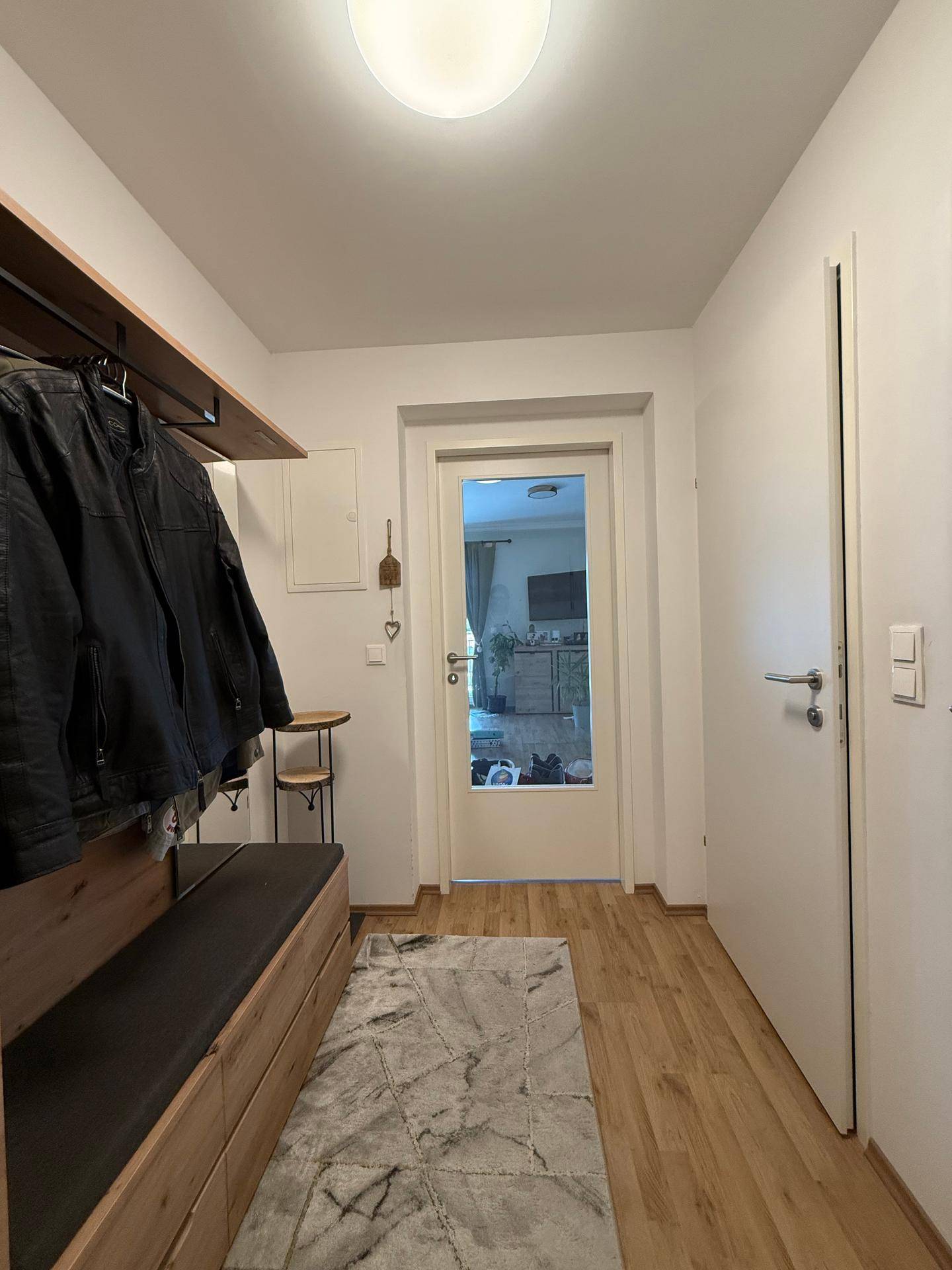 Eingangsbereich mit Garderobe, Holzboden und heller Beleuchtung.