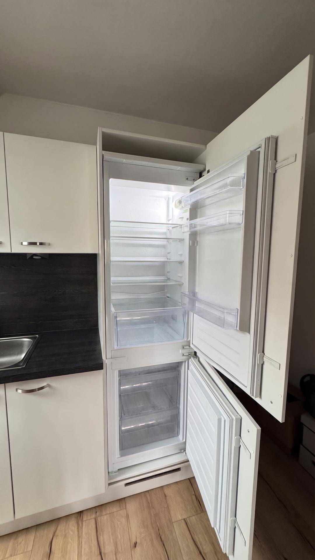 Integrierter Kühlschrank in der Küchenzeile mit ausreichend Stauraum für Lebensmittel.