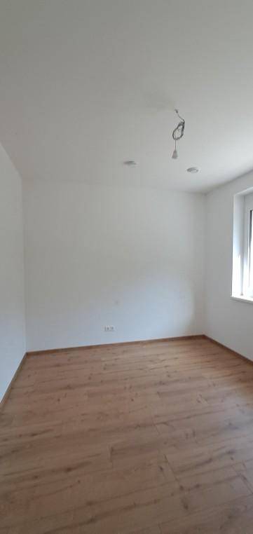 Unmöblierter Raum mit hellem Laminatboden und schlichten weißen Wänden, ideal für individuelle Gestaltung.
