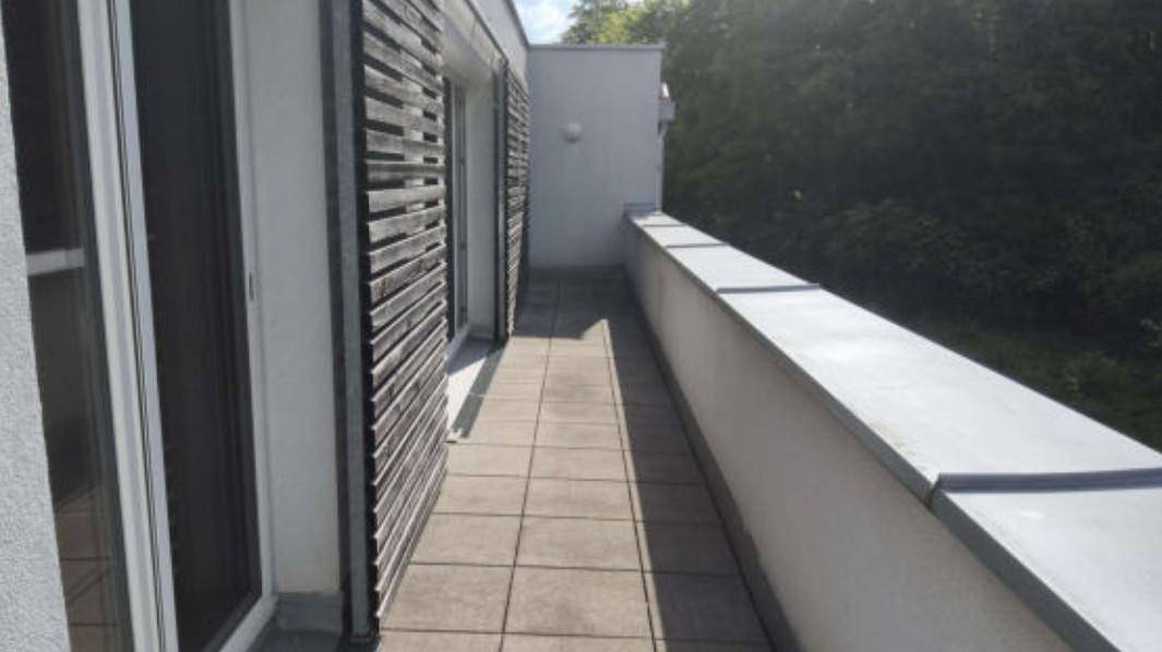 Schmaler Balkon mit Fliesenboden und modernen Holzlamellen als Sichtschutz.