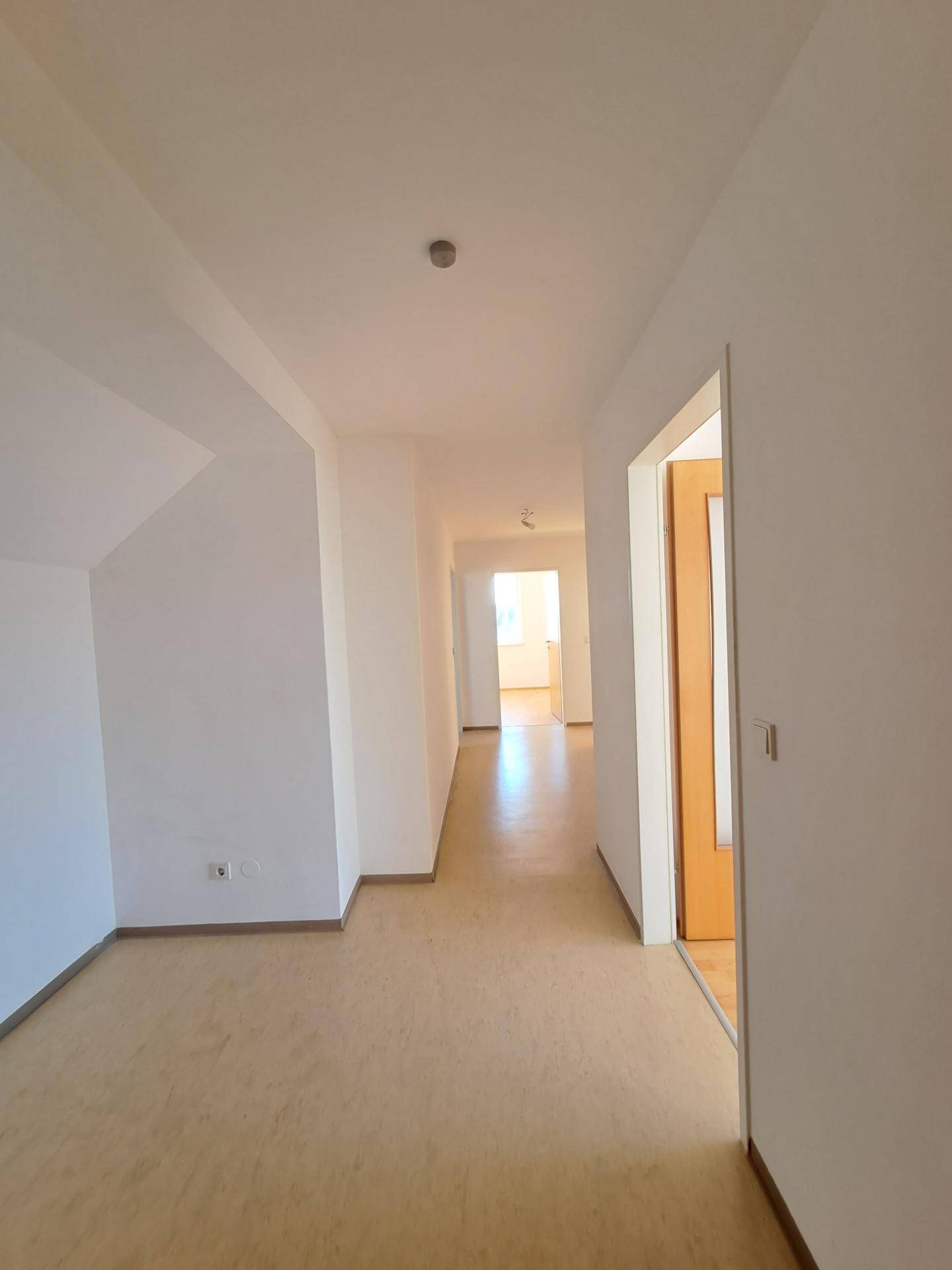 Heller Flur mit Laminatboden, der zu weiteren Zimmern der Wohnung führt.