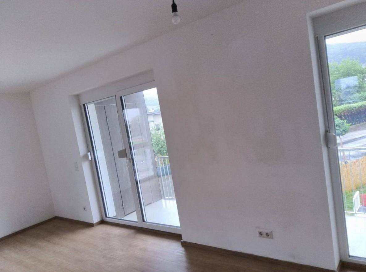 Heller Raum mit großen Fenstern und Balkontüren, die viel Tageslicht hereinlassen.