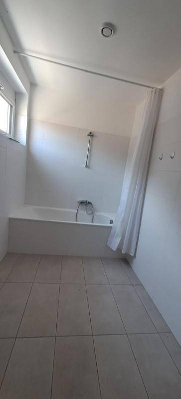 Funktionales Badezimmer mit Badewanne, Duschvorhang und Fenster für Tageslicht.